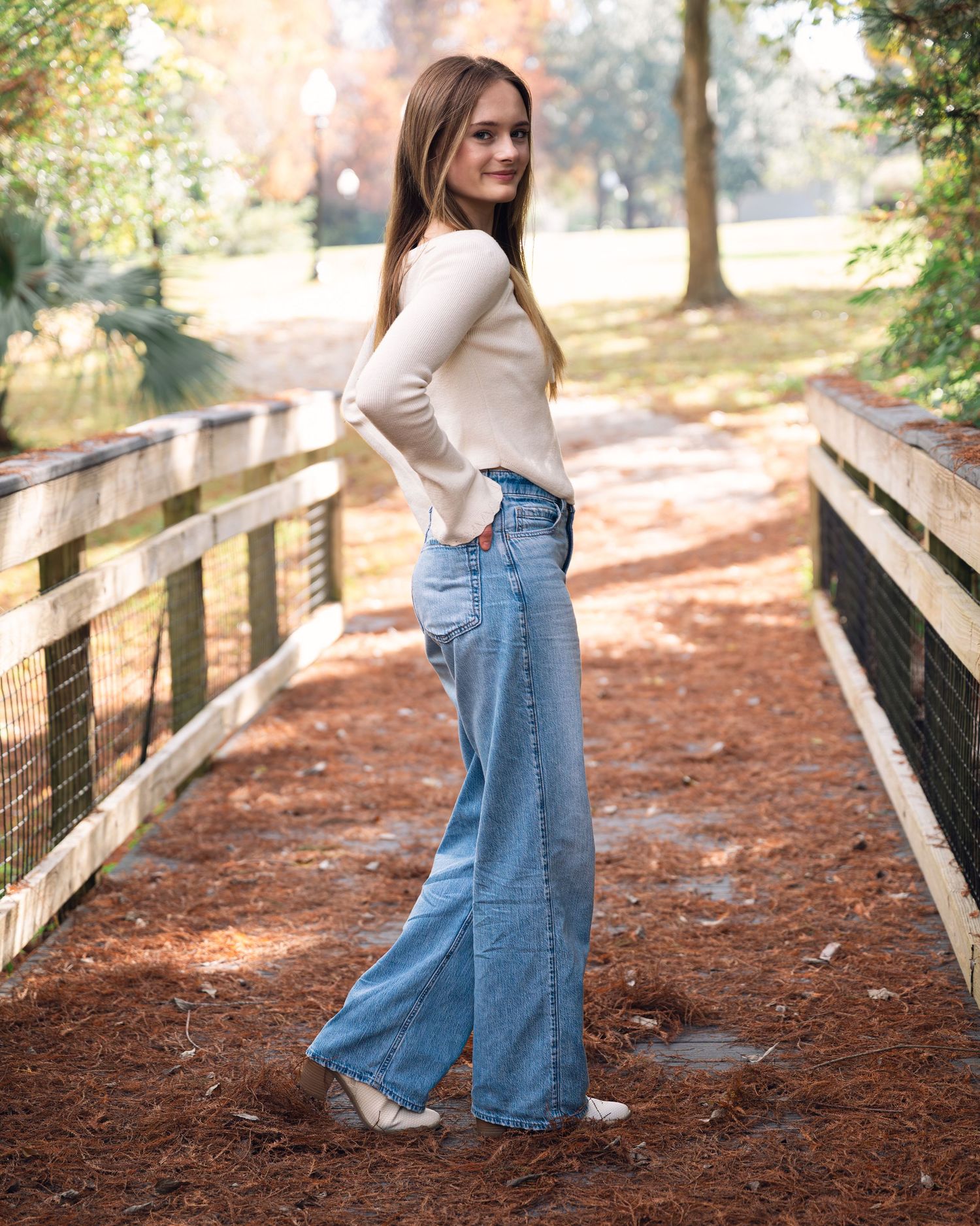 Candid fashion shots on wooden boardwalk featuring casual denim and cream sweater combination.