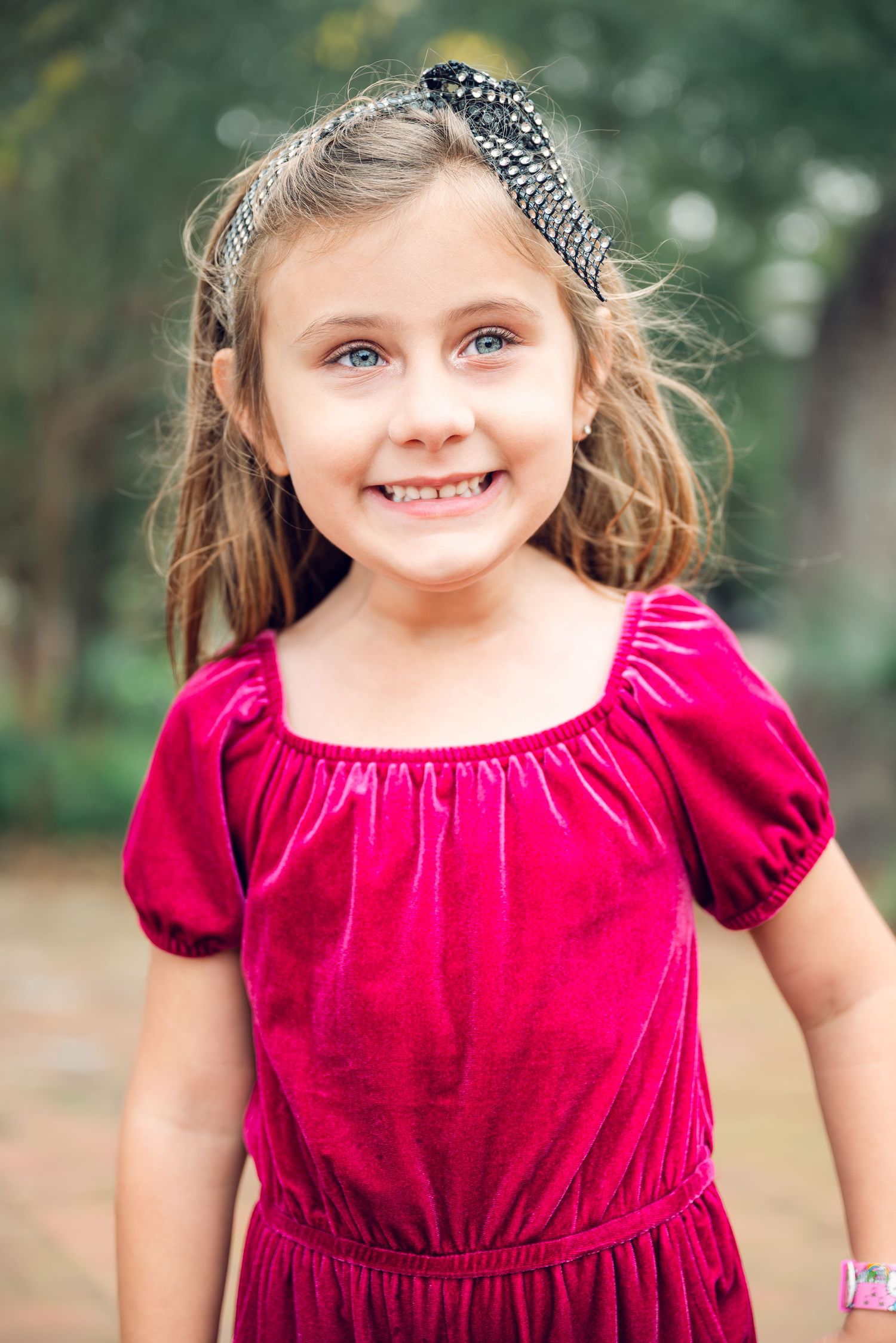 Series of cheerful poses in red velvet dress with sparkly headband in outdoor setting.
