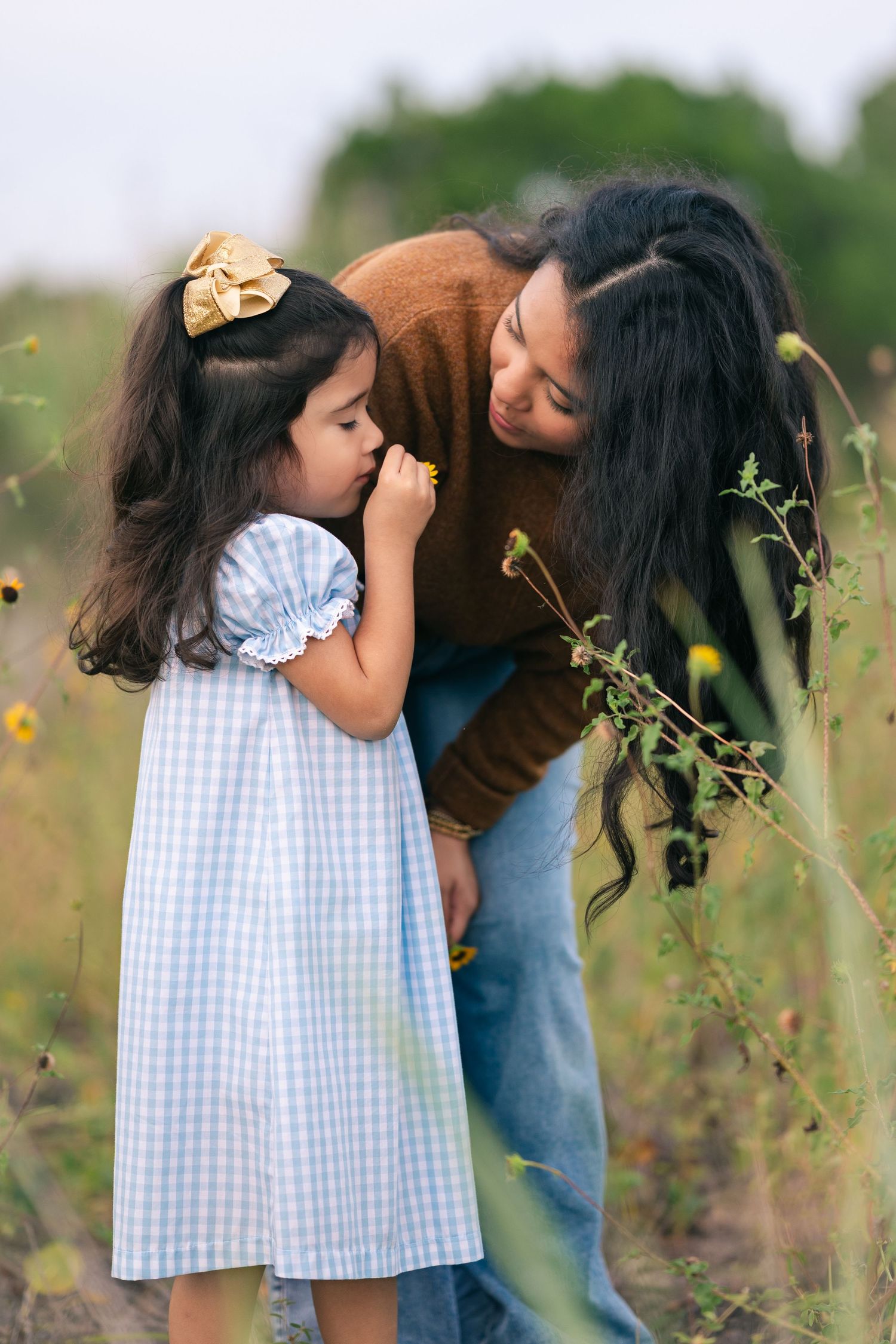 Two people share an intimate moment in a field of wildflowers at sunset.