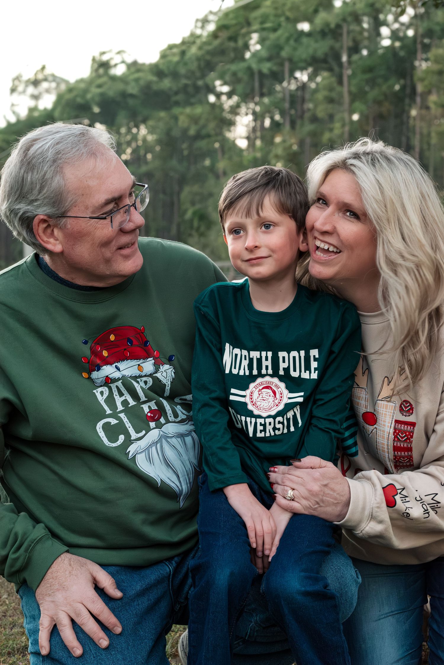 Family wearing matching holiday sweaters posing together outdoors.