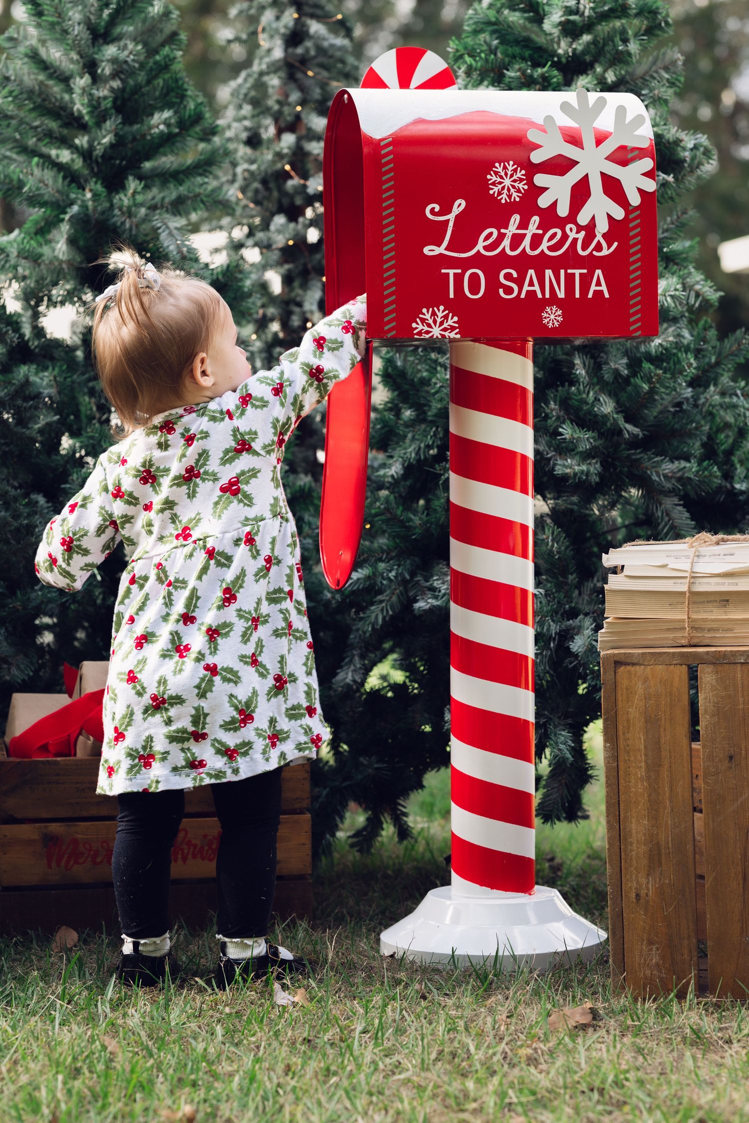 Red and white striped Santa mailbox display with Christmas trees in background.