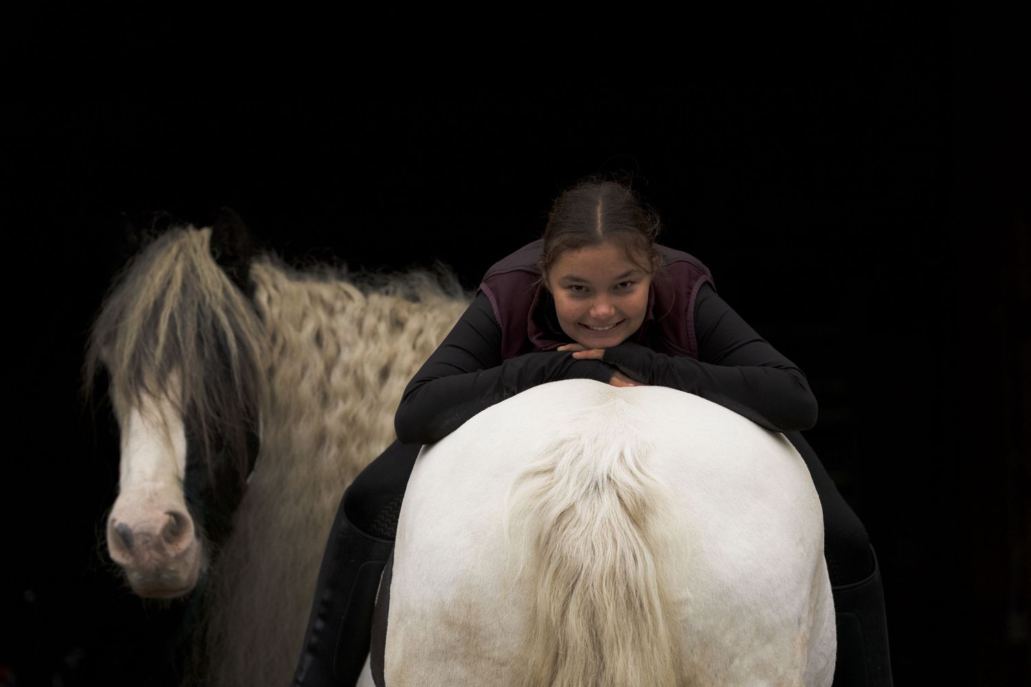 Blackfoto van een Tinker met verzorgster achterste voren zittend en leunend op de billen van het paard kijkend in de camera