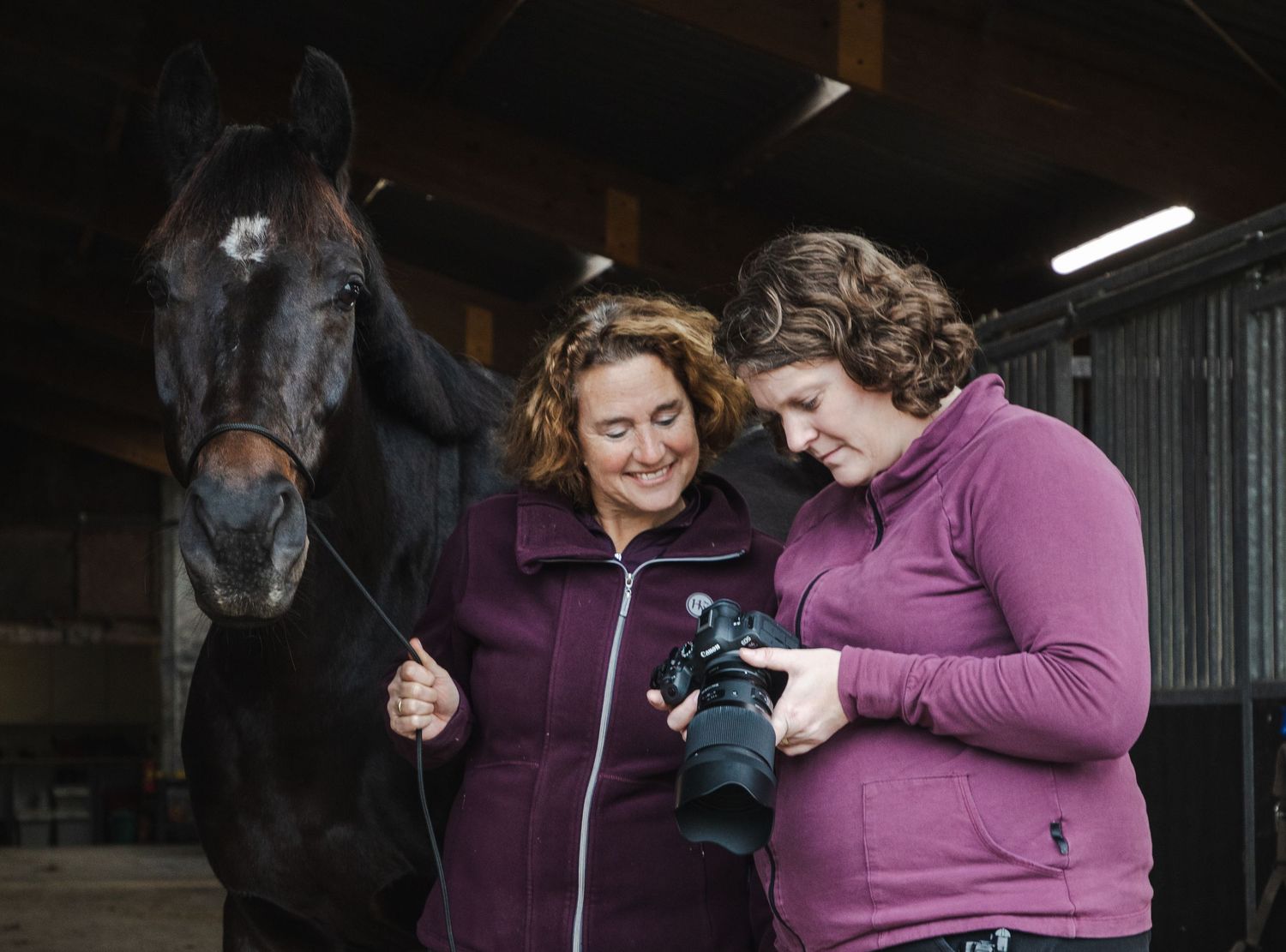 Mariska van Harten, fotograaf bij van Harten Moments, laat foto's op de camera zien aan de modellen (paard en mens)