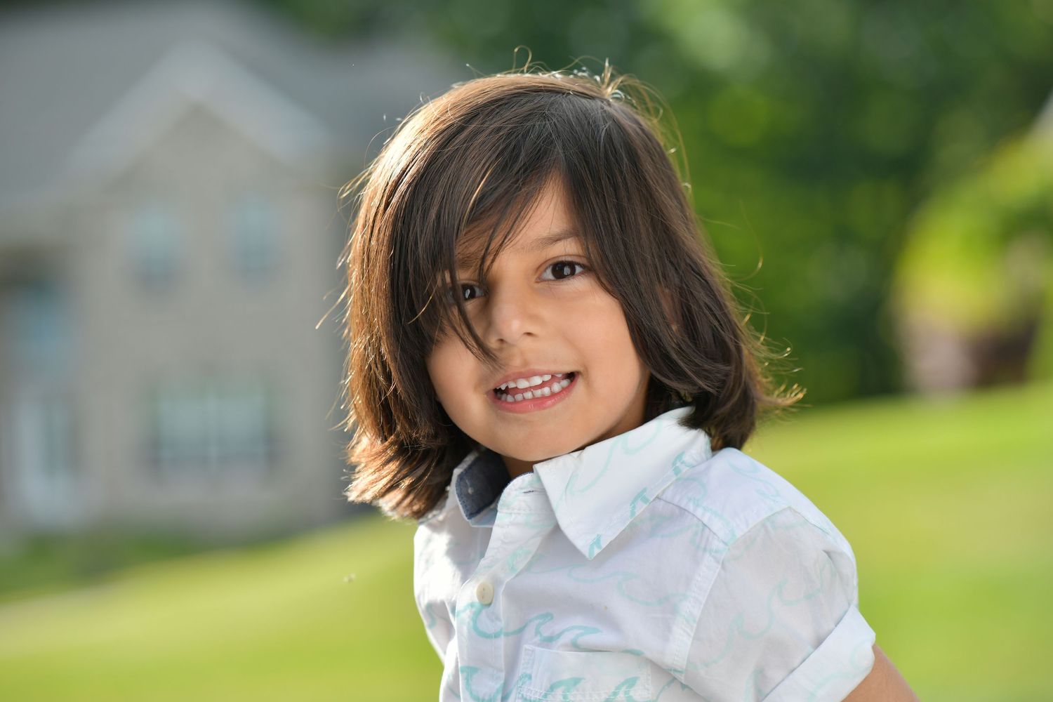 Child wearing white collared shirt photographed in sunny outdoor setting.