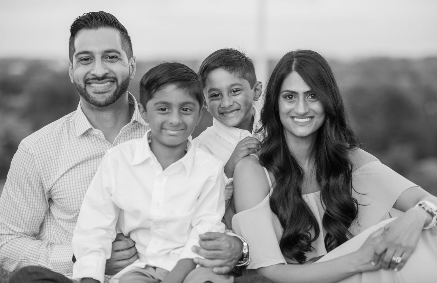 Black and white family portrait series with matching white shirts against neutral background.