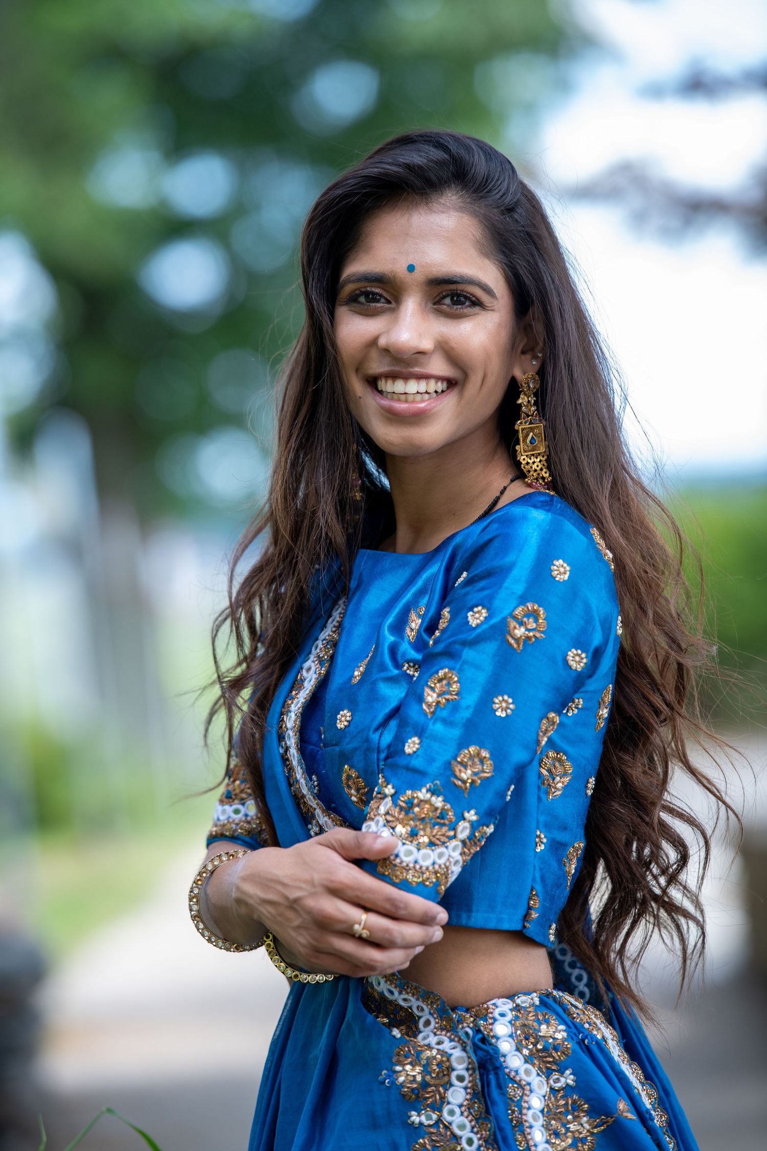 A bright blue traditional embroidered outfit sparkles in outdoor natural lighting.