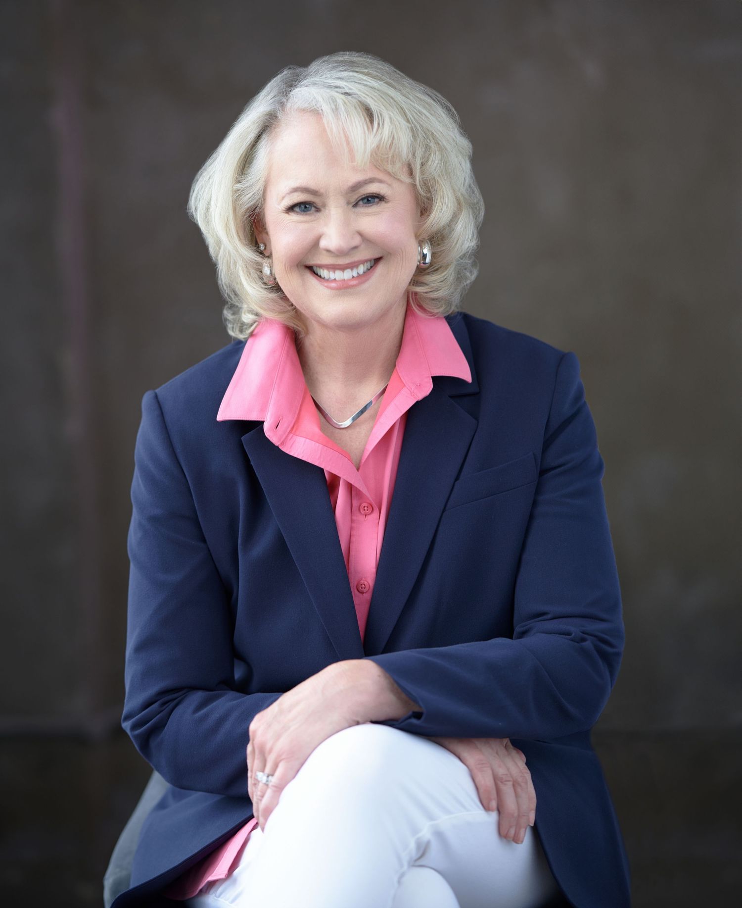 Professional portrait series showing a person in a navy blazer and pink top against a dark background.