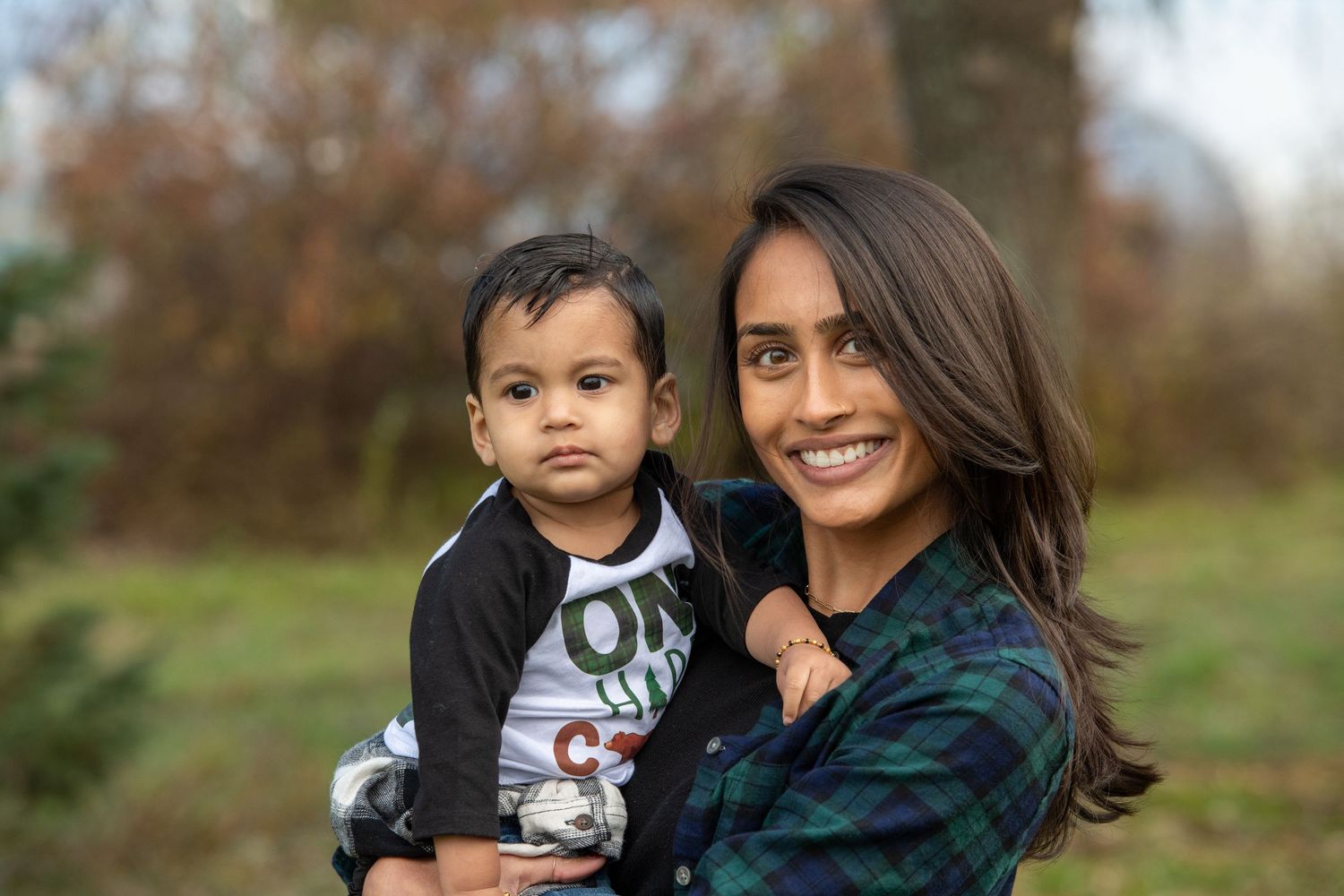 Mother and child in outdoor autumn setting wearing coordinated dark outfits.