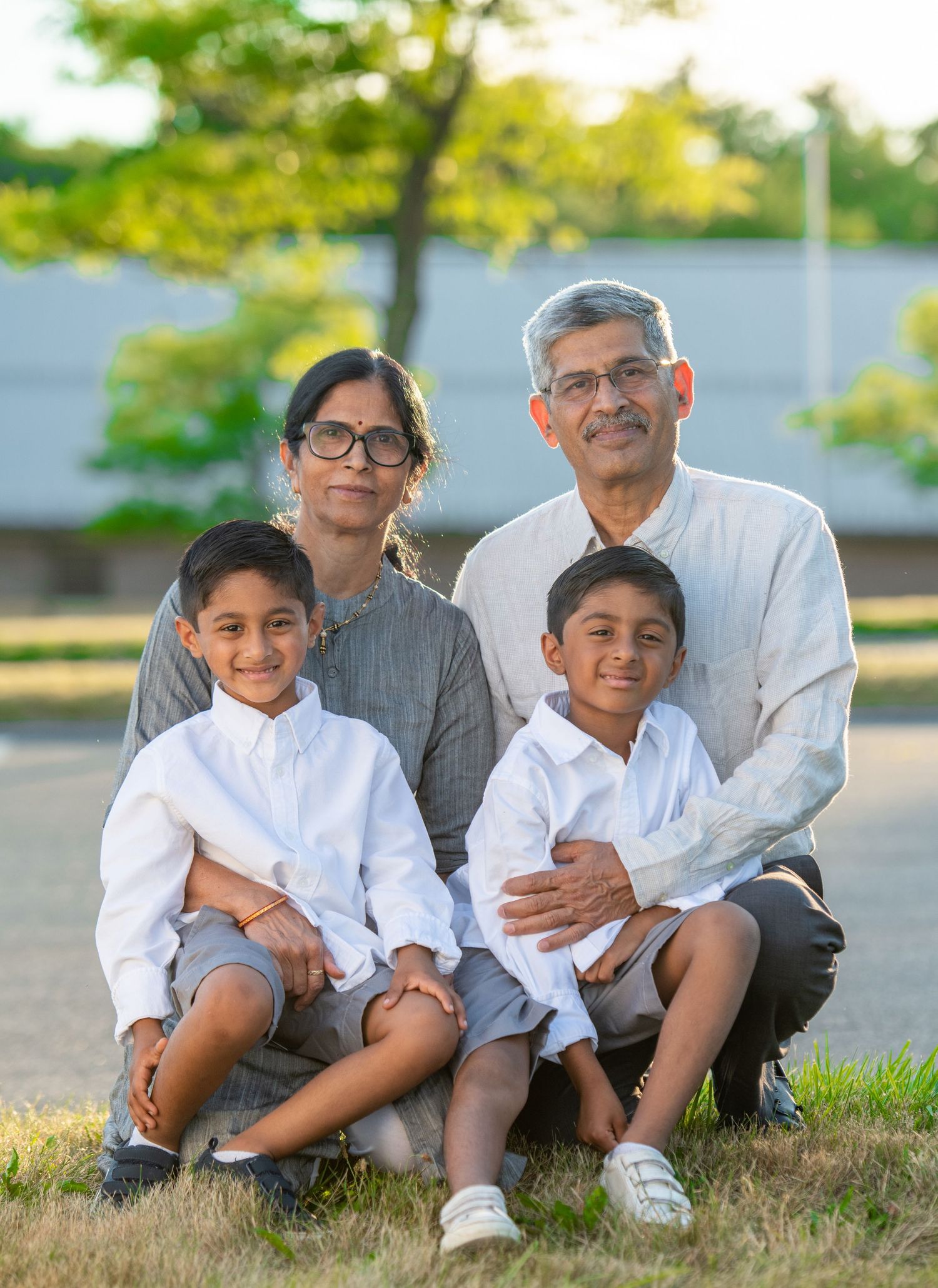 Outdoor family photo session with casual white shirts sitting on grass.