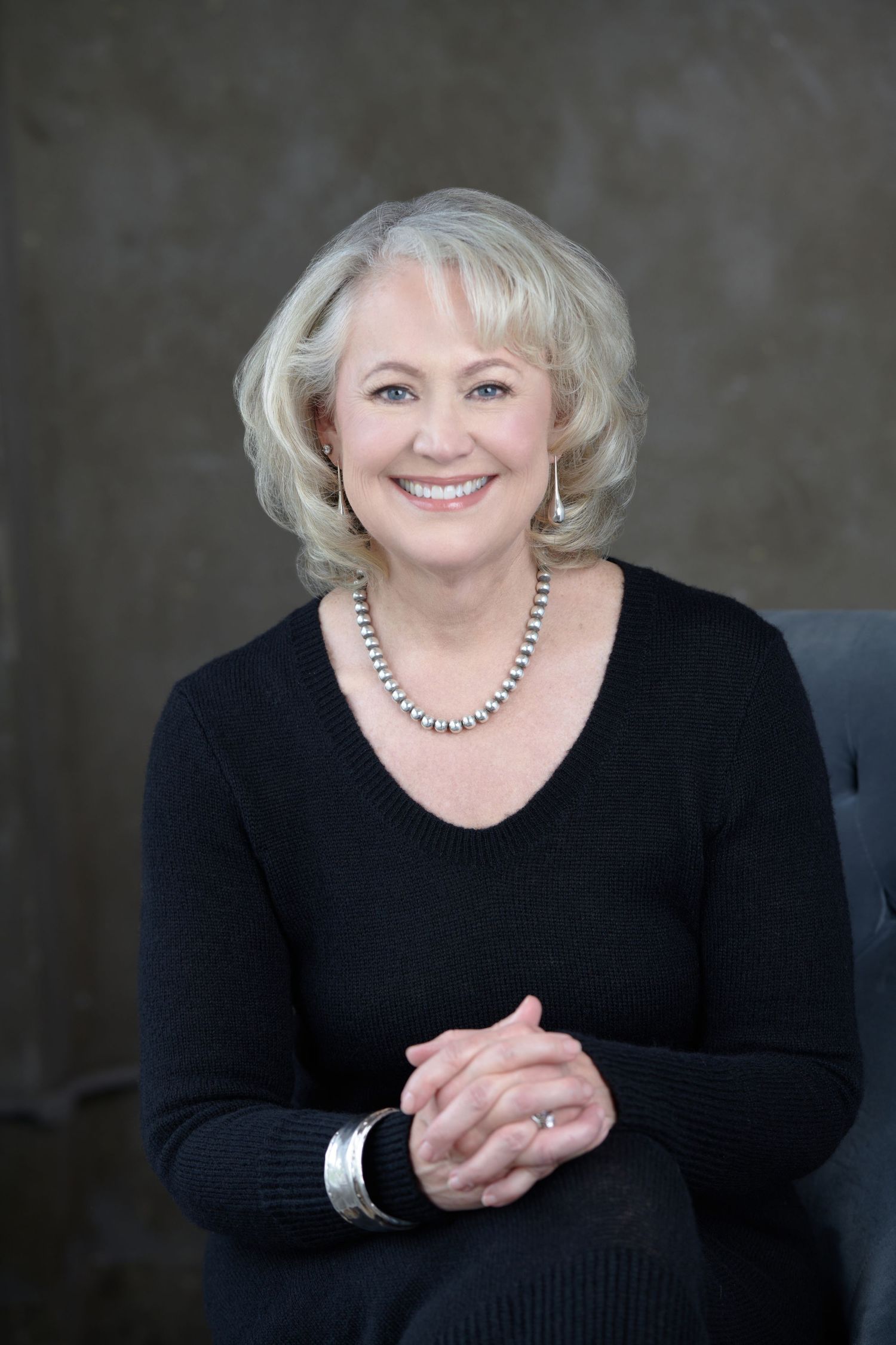 Professional headshot series of a woman in black sweater with silver jewelry against dark background.