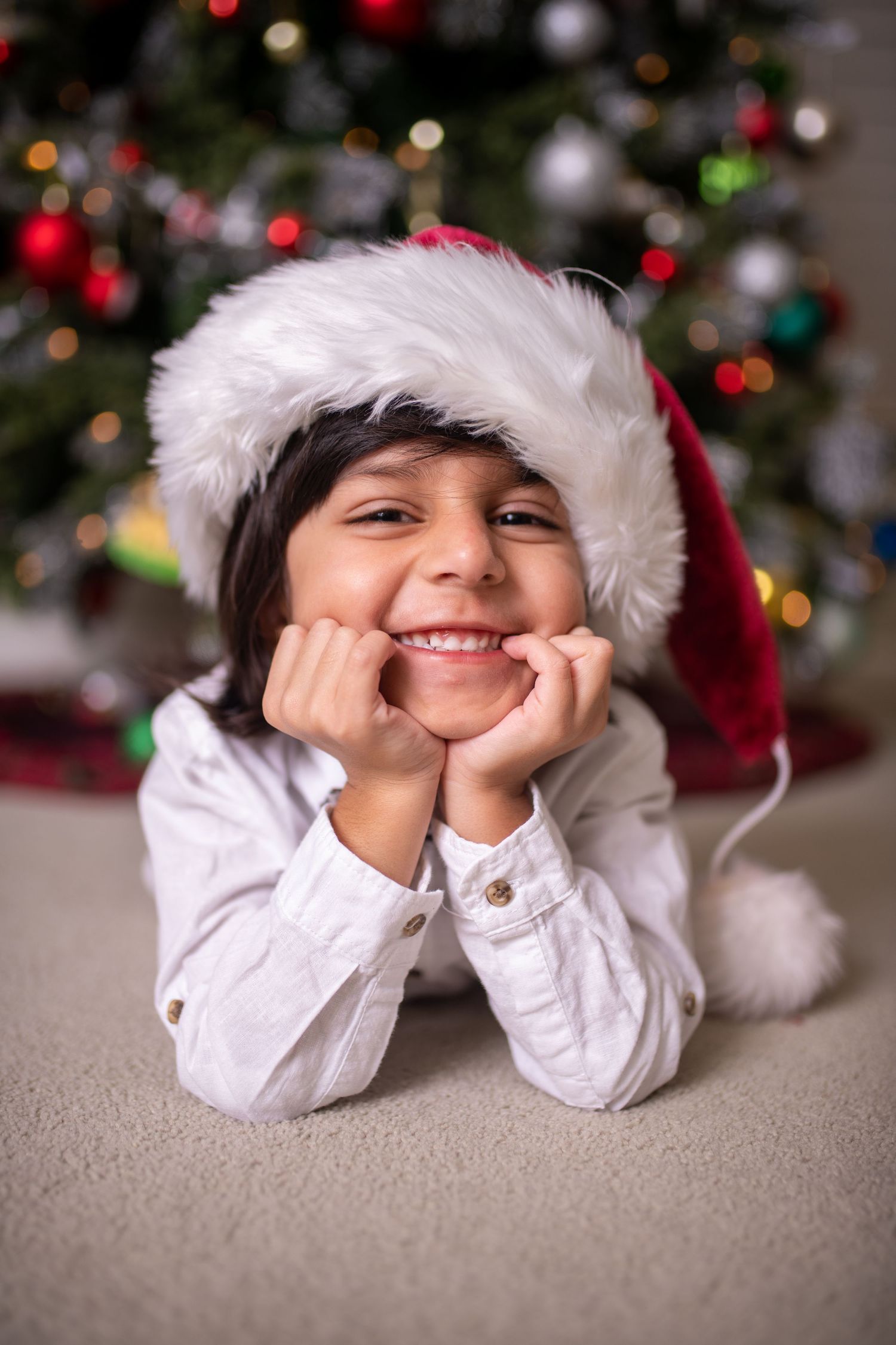 Festive holiday portrait of child in Santa hat with Christmas decorations.