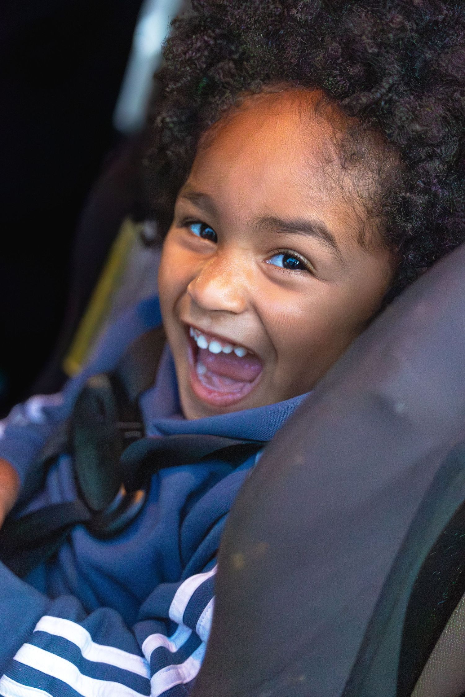 Young child in a car seat smiling with joy and enthusiasm.