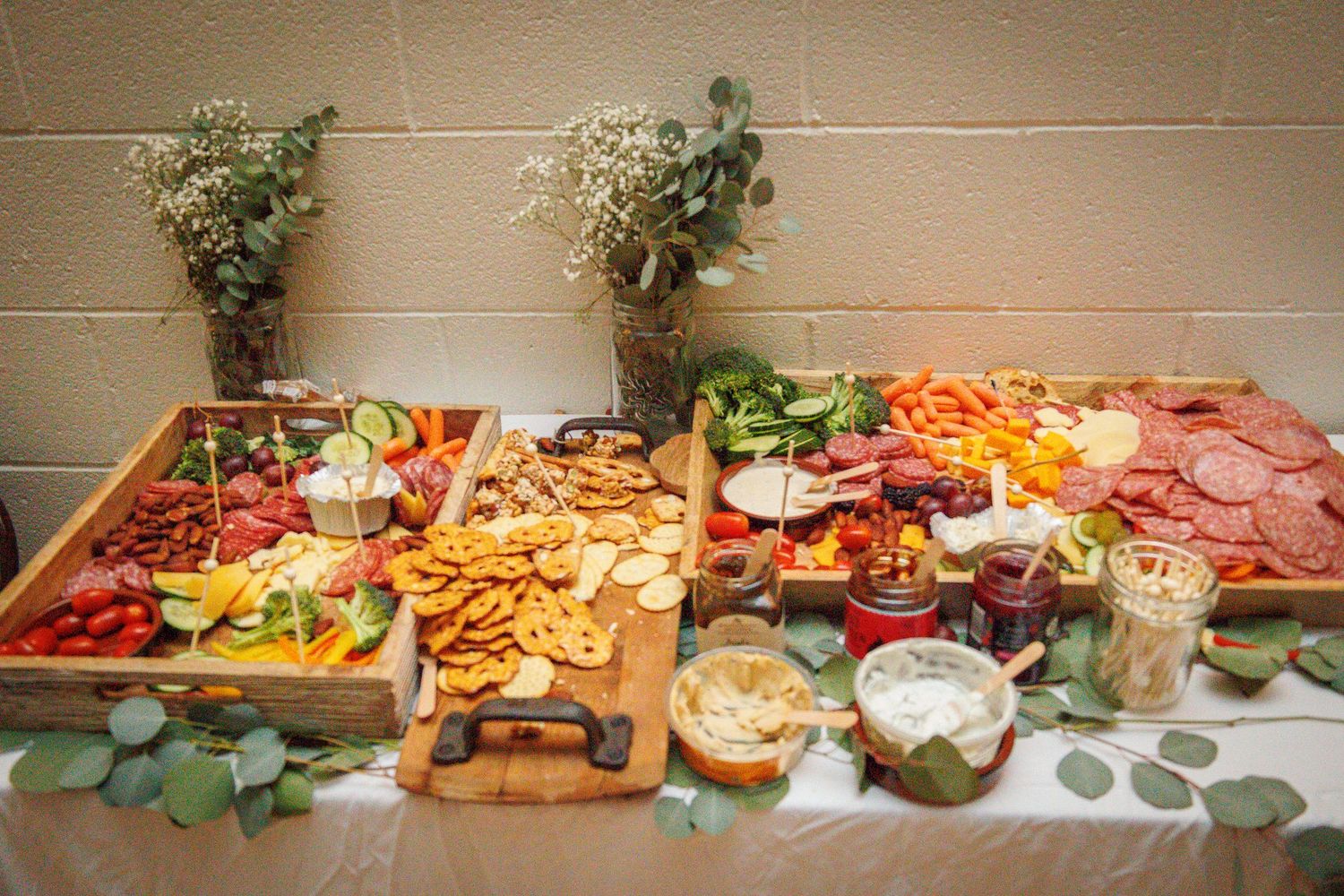 Long table display of various appetizers, snacks and party foods arranged for catering.