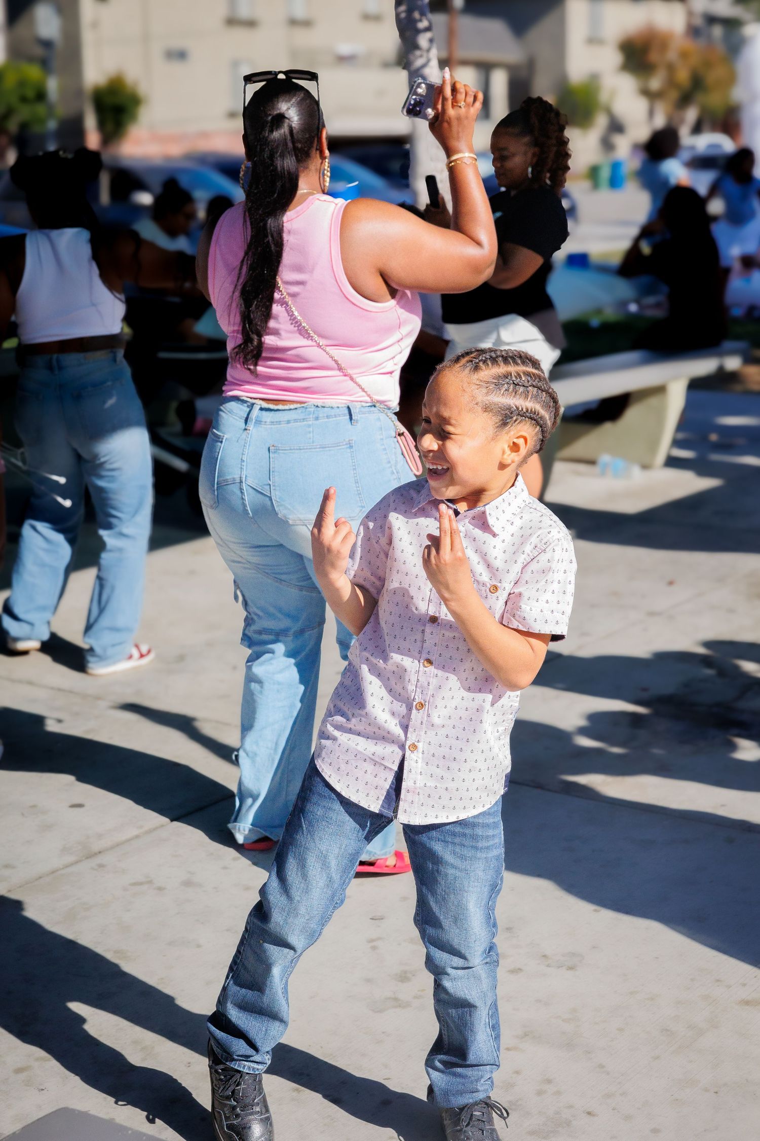 People dancing and celebrating at outdoor gathering with child in foreground.