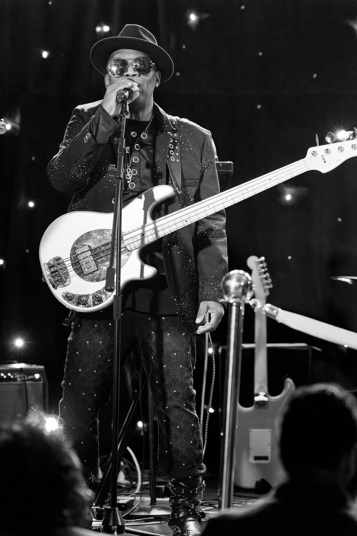Black and white concert photo of musicians performing with bass guitars on a dimly lit stage.