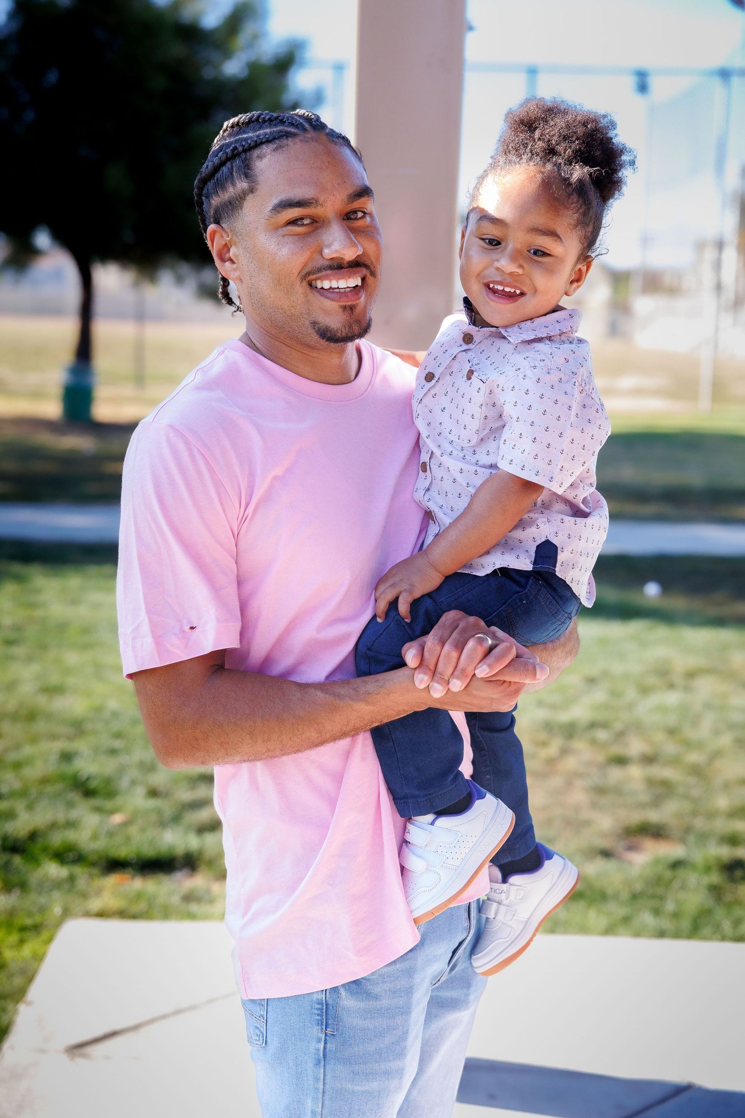 Adult and child sharing joyful moment outdoors in matching pink and white outfits.