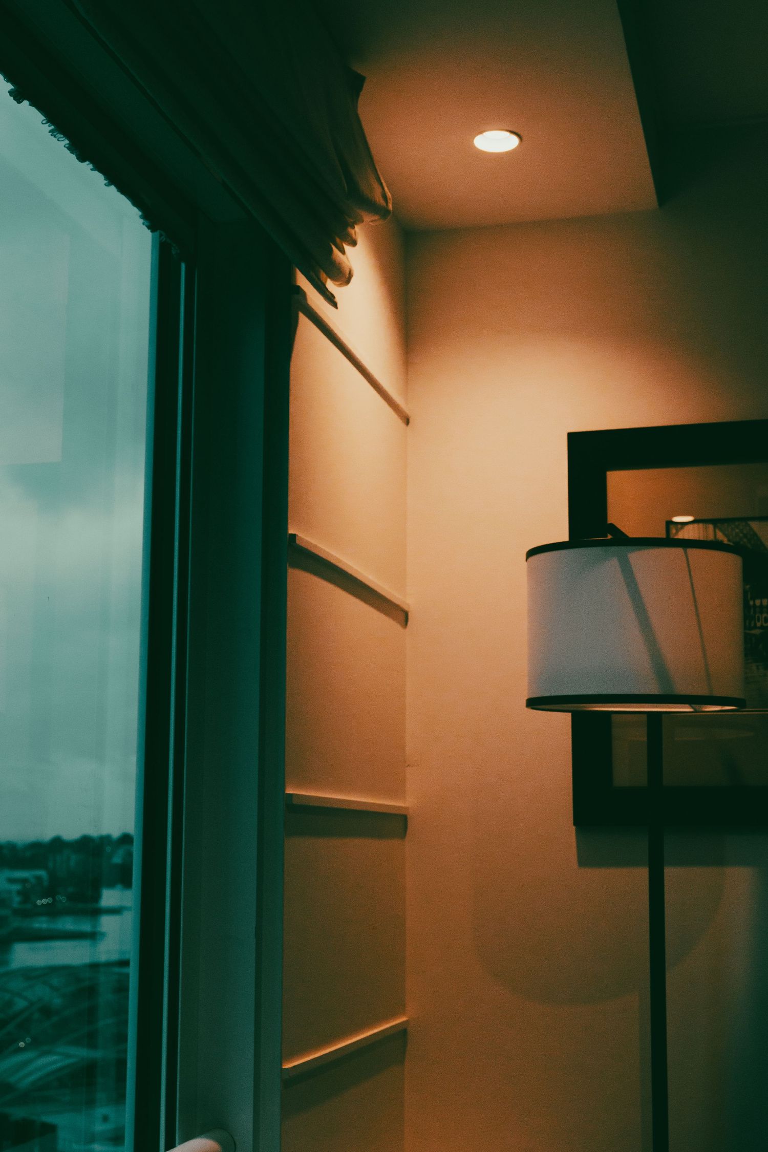 Moody interior shot of a room with warm orange lighting and window silhouettes.