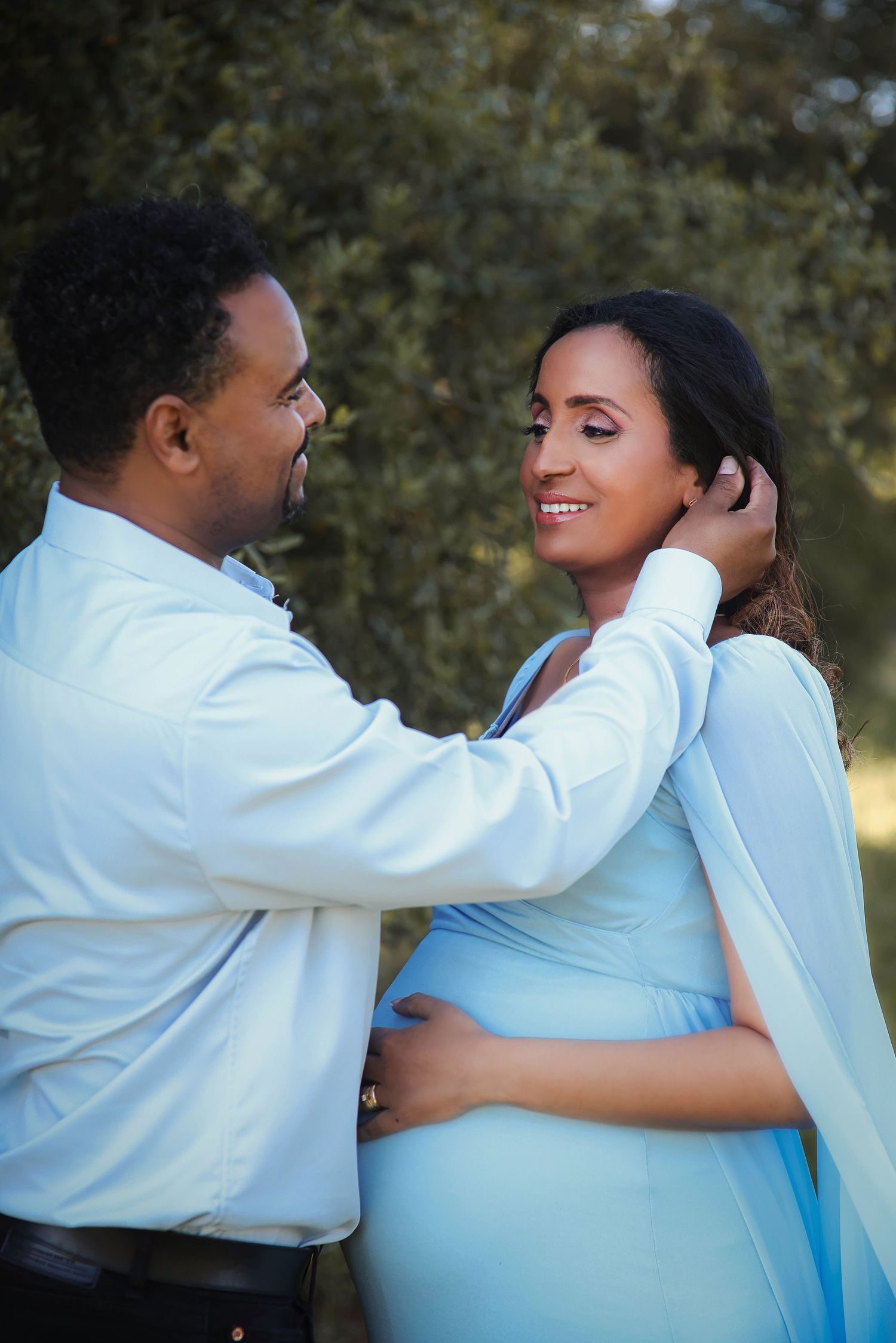 Intimate maternity couple photos in light blue and white outfits.