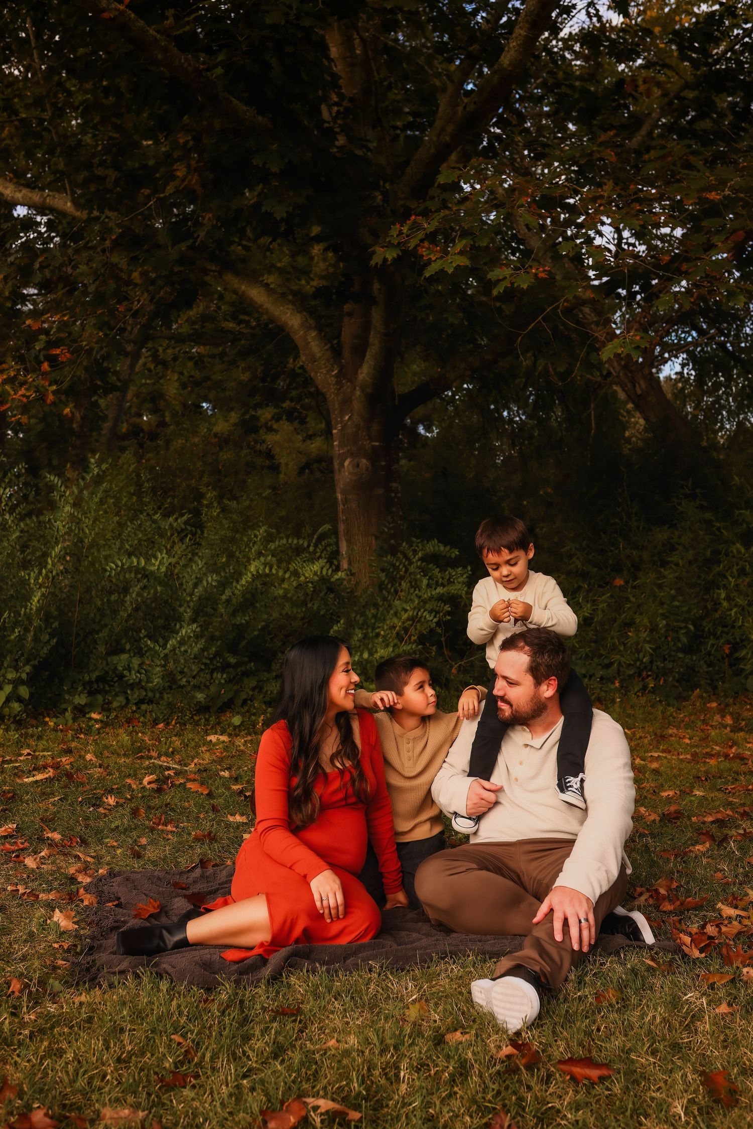 Family relaxing on autumn leaves during golden hour sunset.