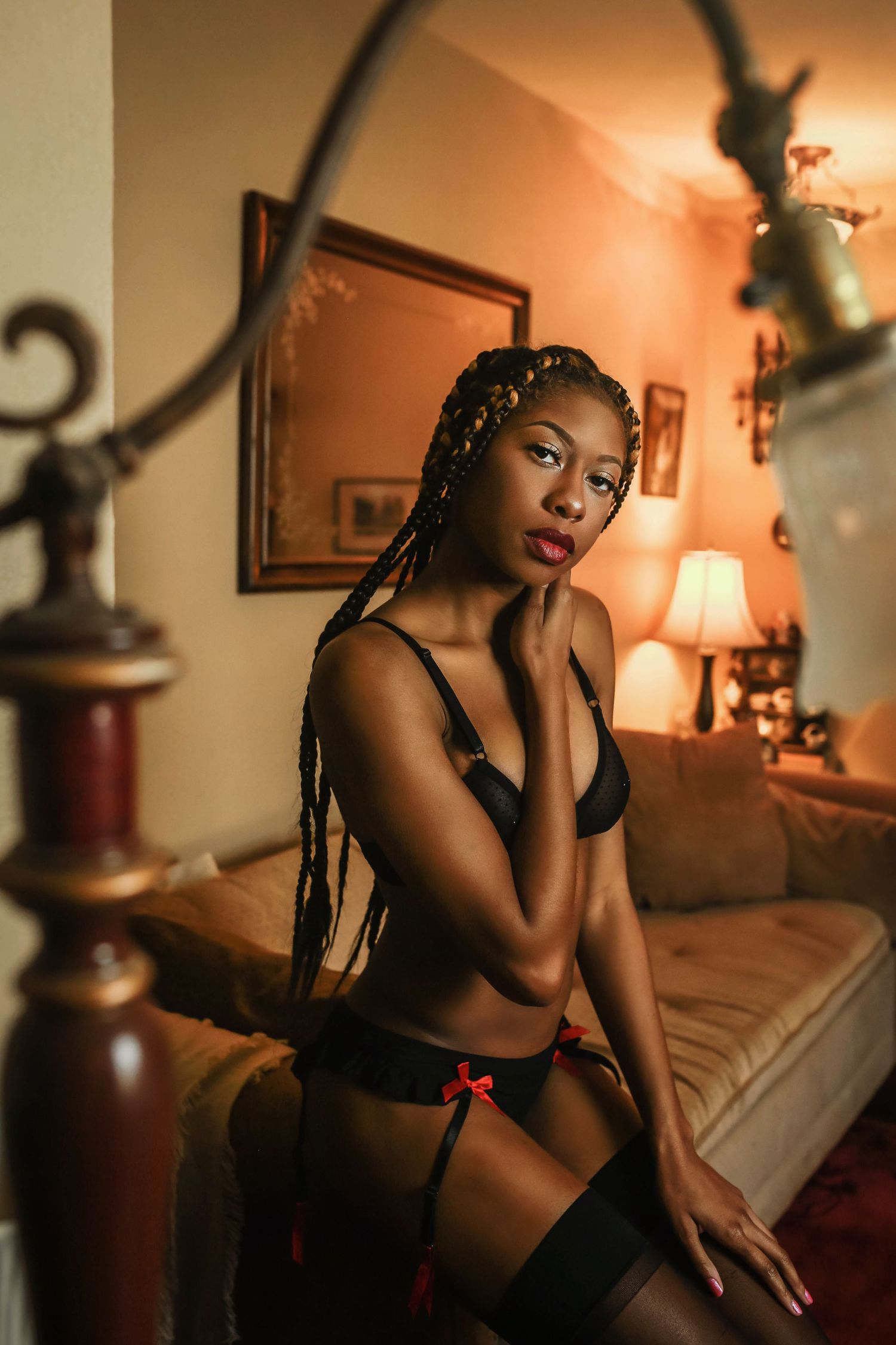 Intimate boudoir portrait in warm lighting with black lingerie and an antique decor setting.