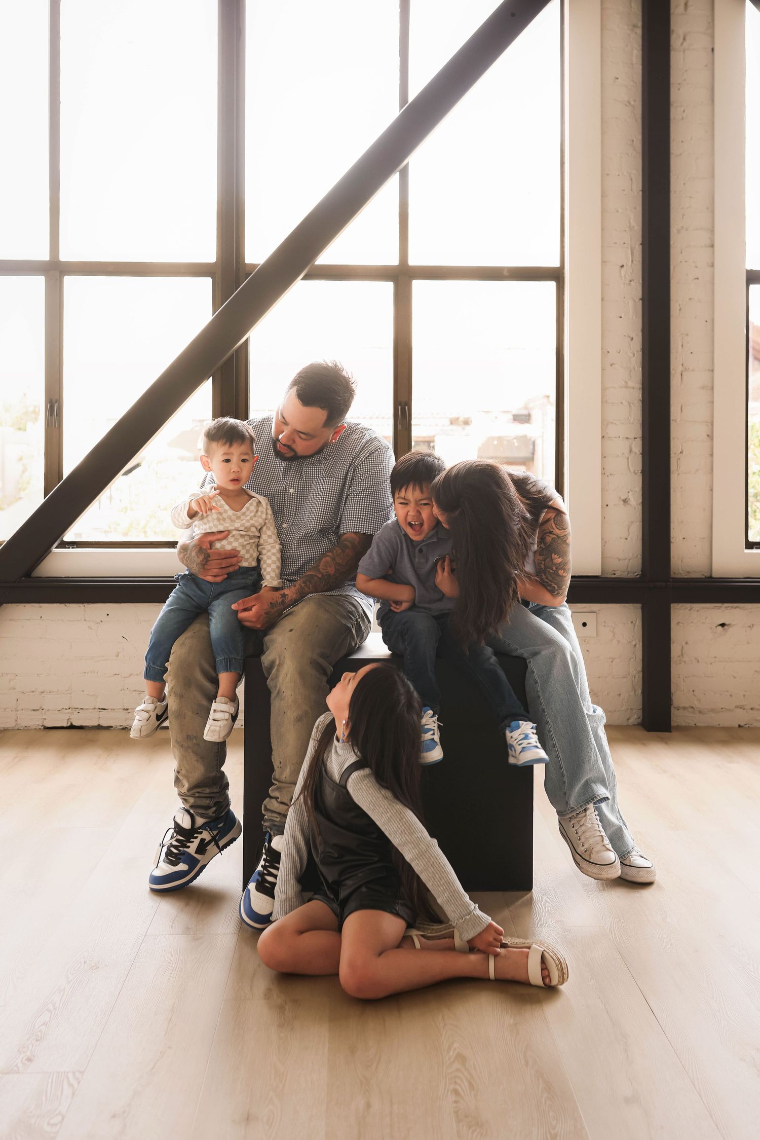 Family sharing casual moment together while sitting on black chair in bright industrial space.