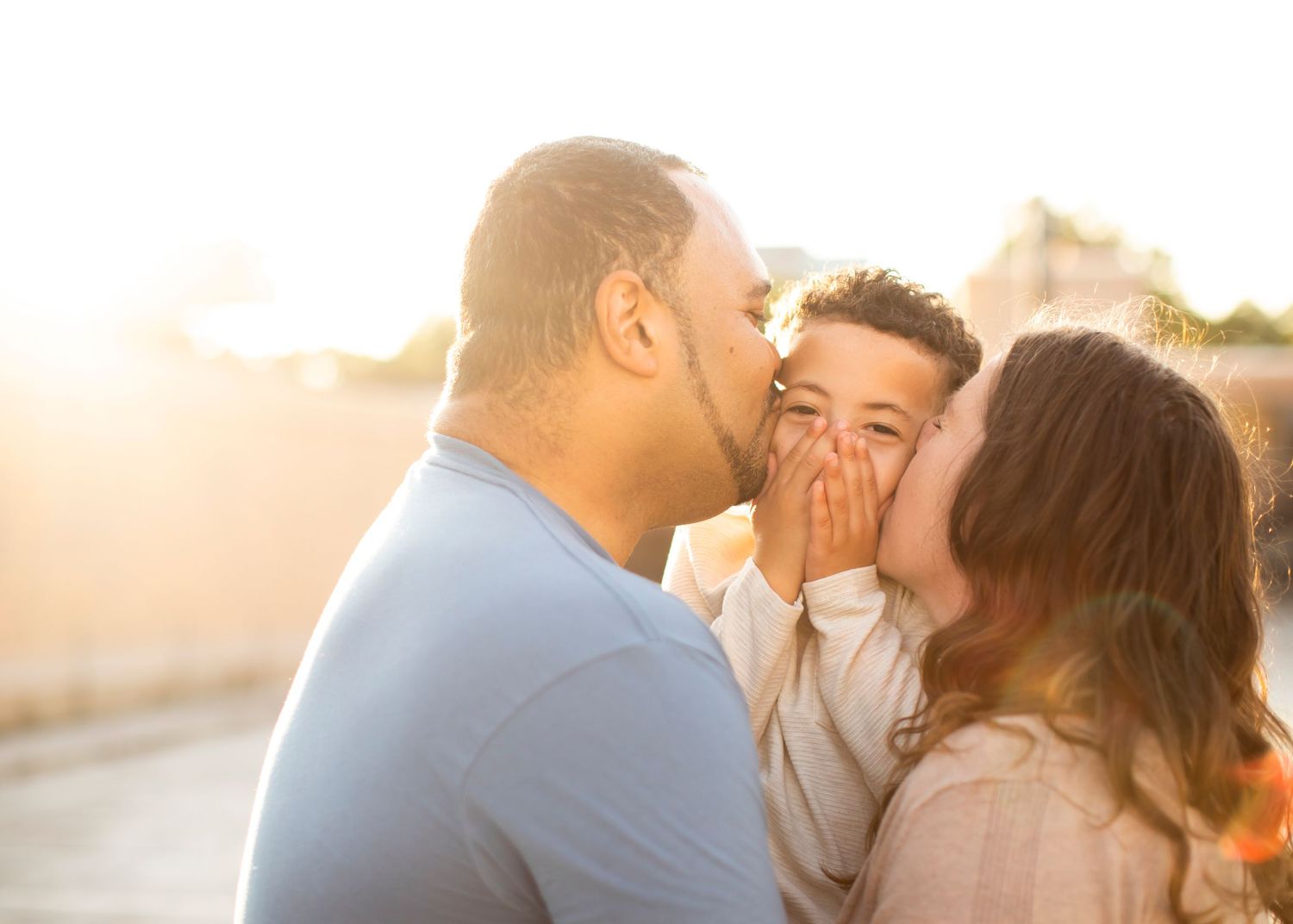 A loving family shares a tender moment together outdoors during golden hour sunset.