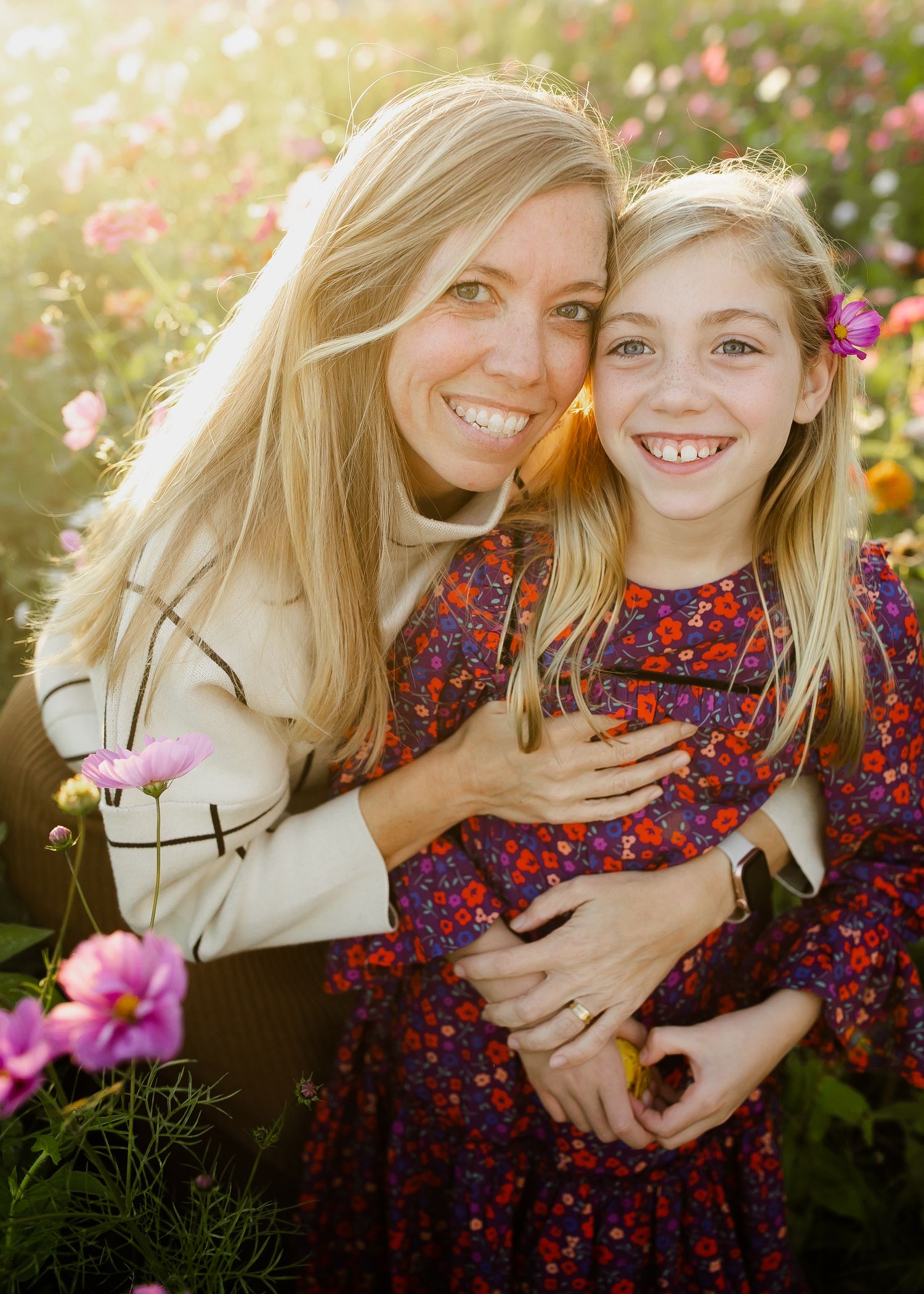 A pair in a joyful embrace among blooming pink flowers in a garden setting.