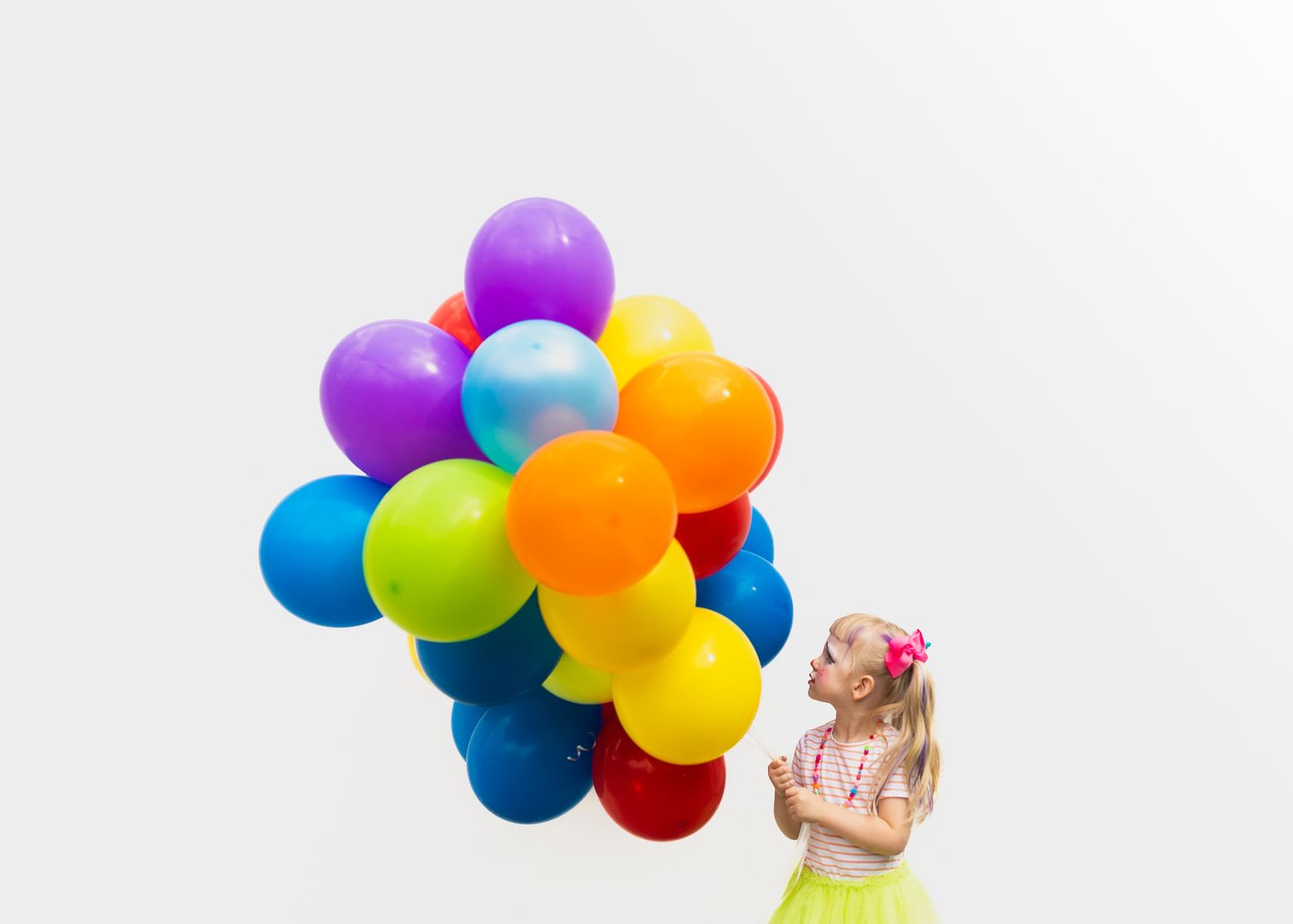 A person holds a vibrant bunch of colorful balloons against a bright white background.