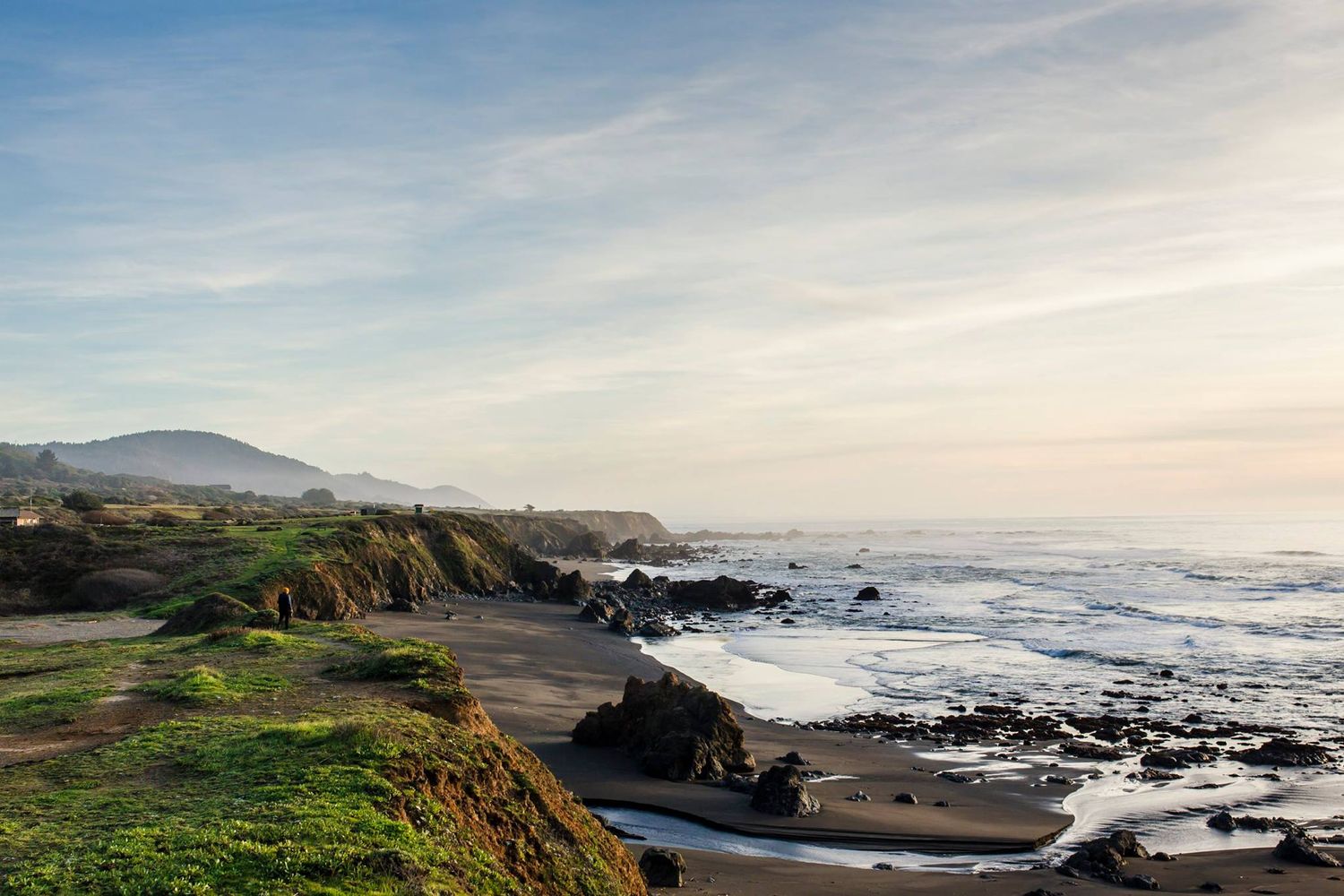 Panoramic view of rugged coastal cliffs and rocky beaches along the Pacific Ocean during sunset.