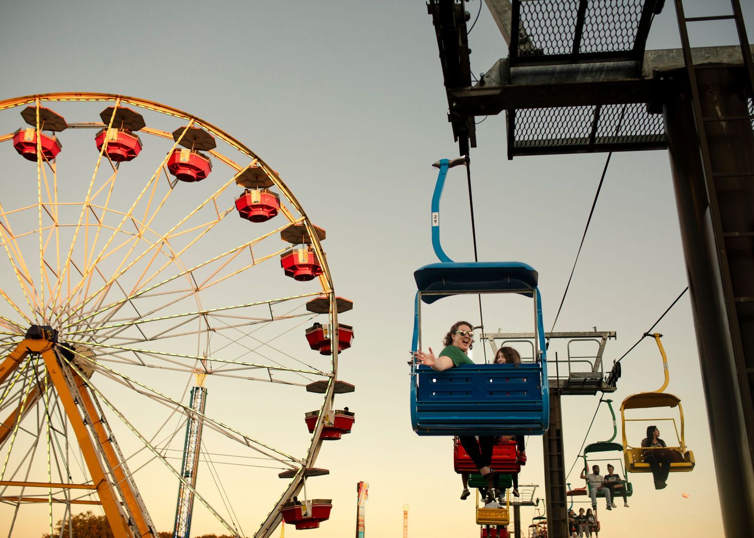 Silhouetted carnival rides and attractions at sunset create a nostalgic amusement park skyline.
