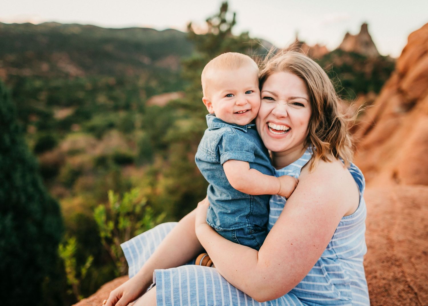 A blissful moment shared between two people sitting on red rocks with scenic mountain views in the background.