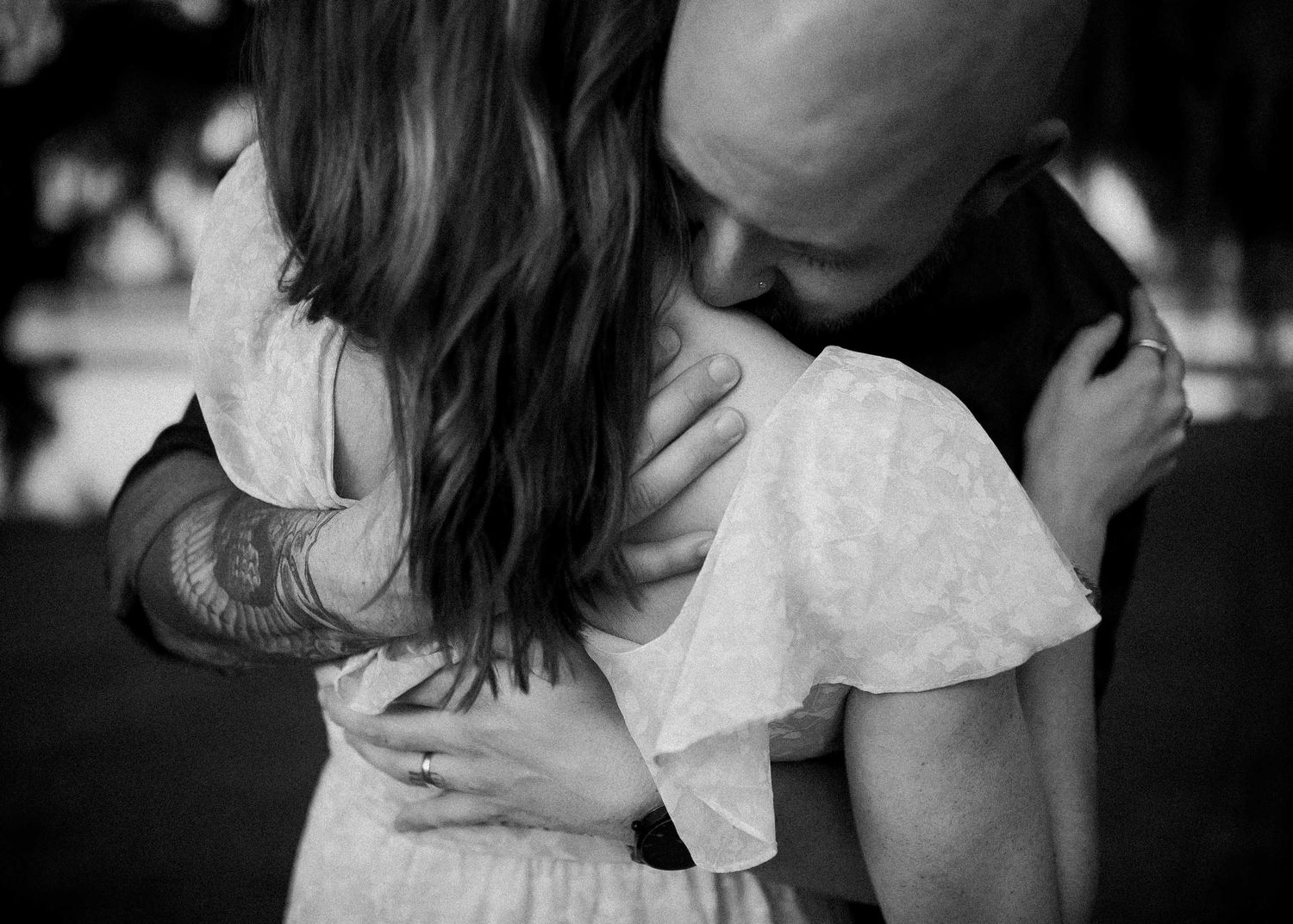 A black and white photo showing an intimate moment between two people in close embrace.