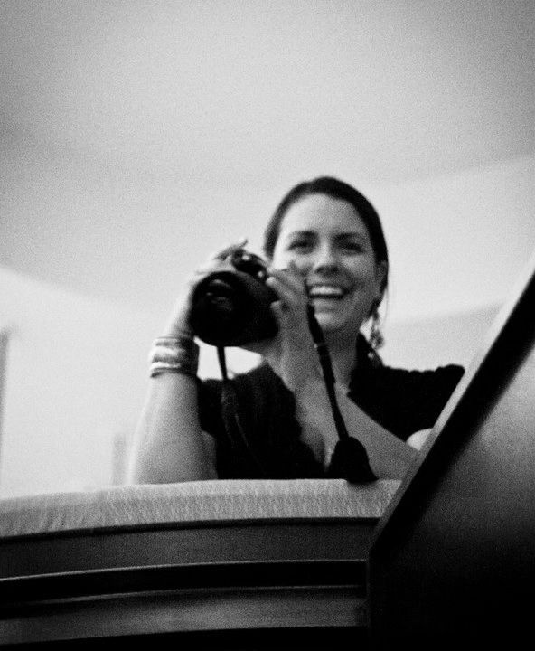 Black and white photo of Amaris smiling and holding her camera.