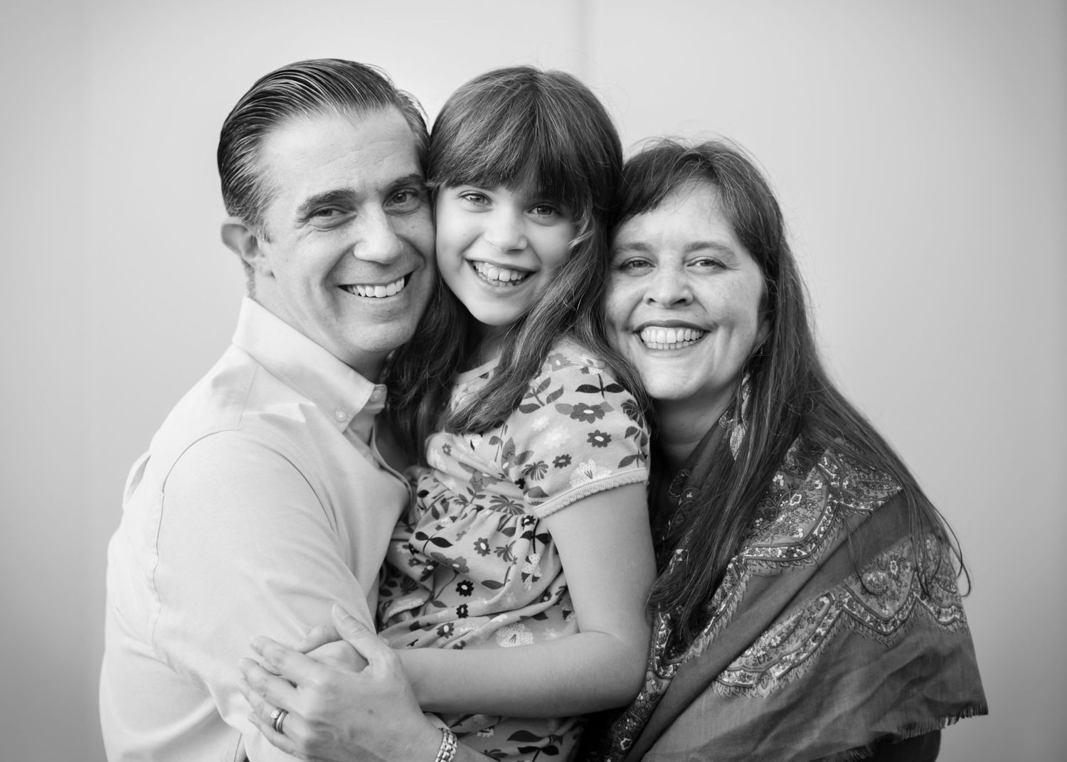 Black and white family portrait series showing loving embraces and joyful moments together in casual attire.