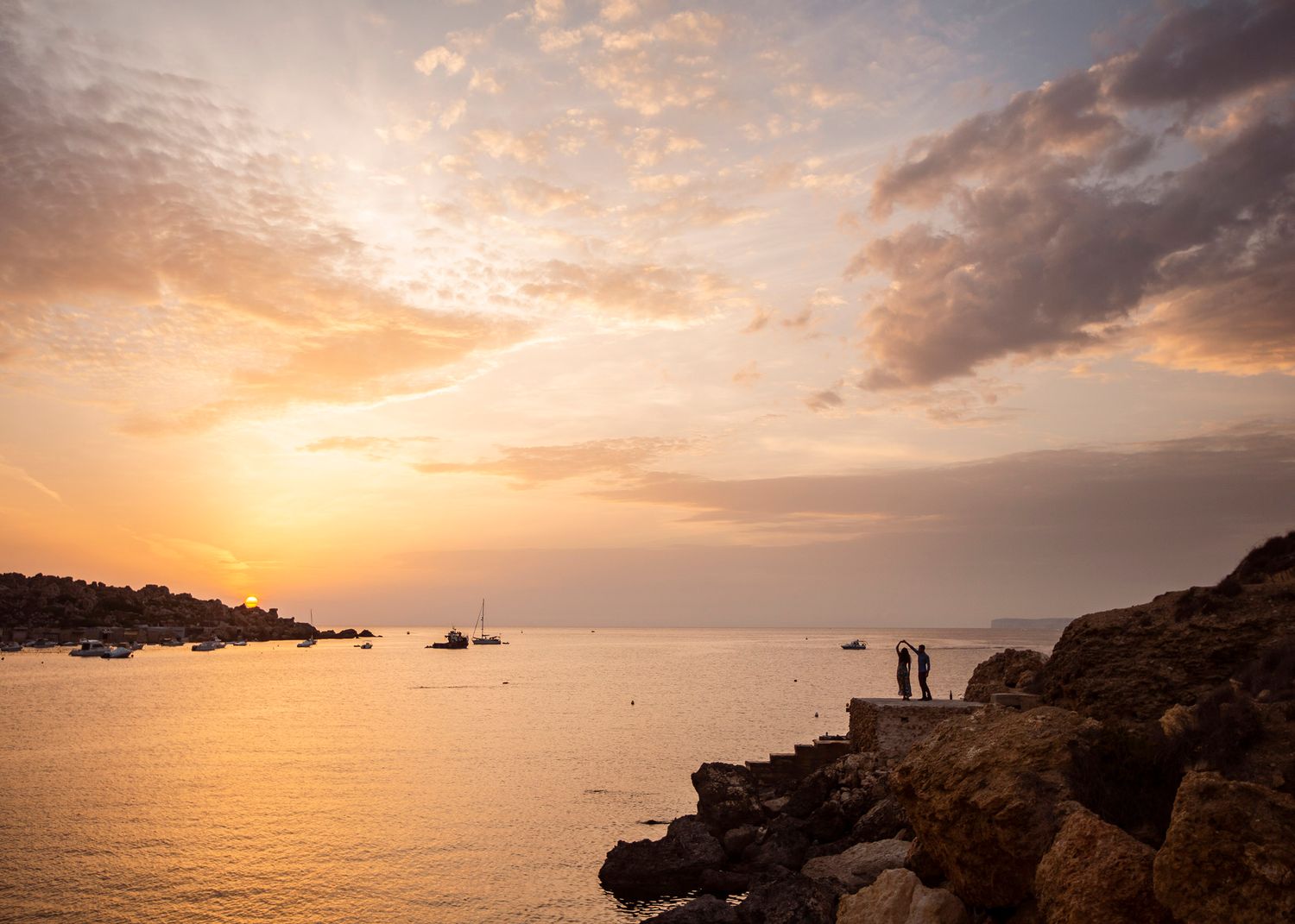 A view of a couple spinning on the edge of the mountains in Malta.