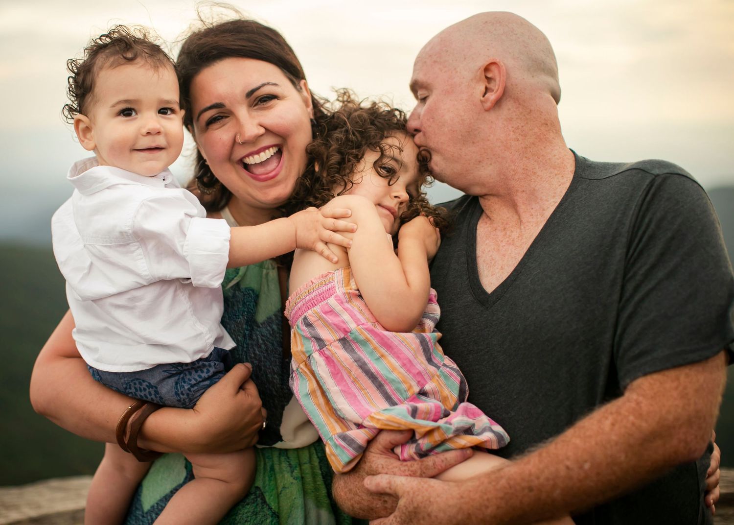 A loving family shares a cheerful moment together during an outdoor photo session at sunset.