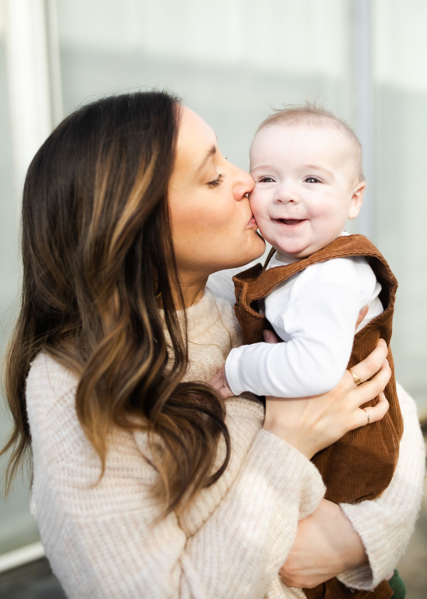 A tender moment between a parent and baby against a bright background.