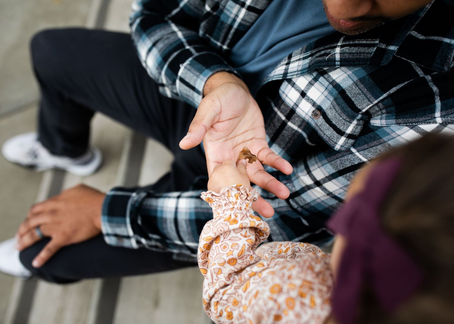 An adult and child hold hands. Their faces are not shown.