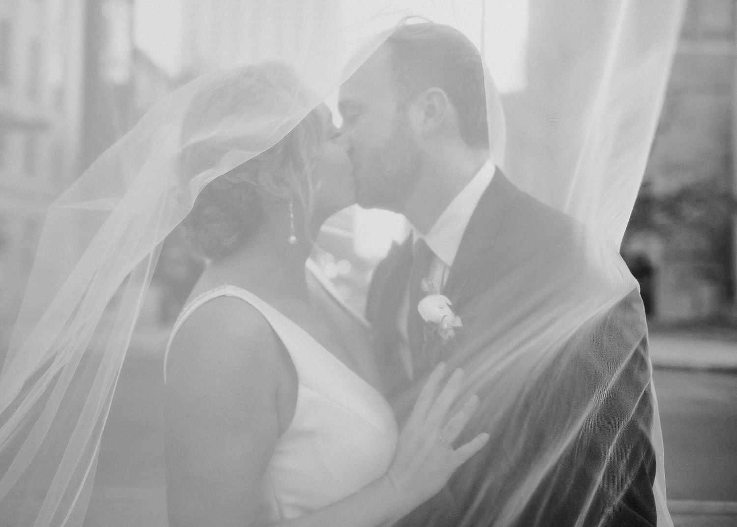 A bride and groom share a romantic kiss under a flowing white veil.