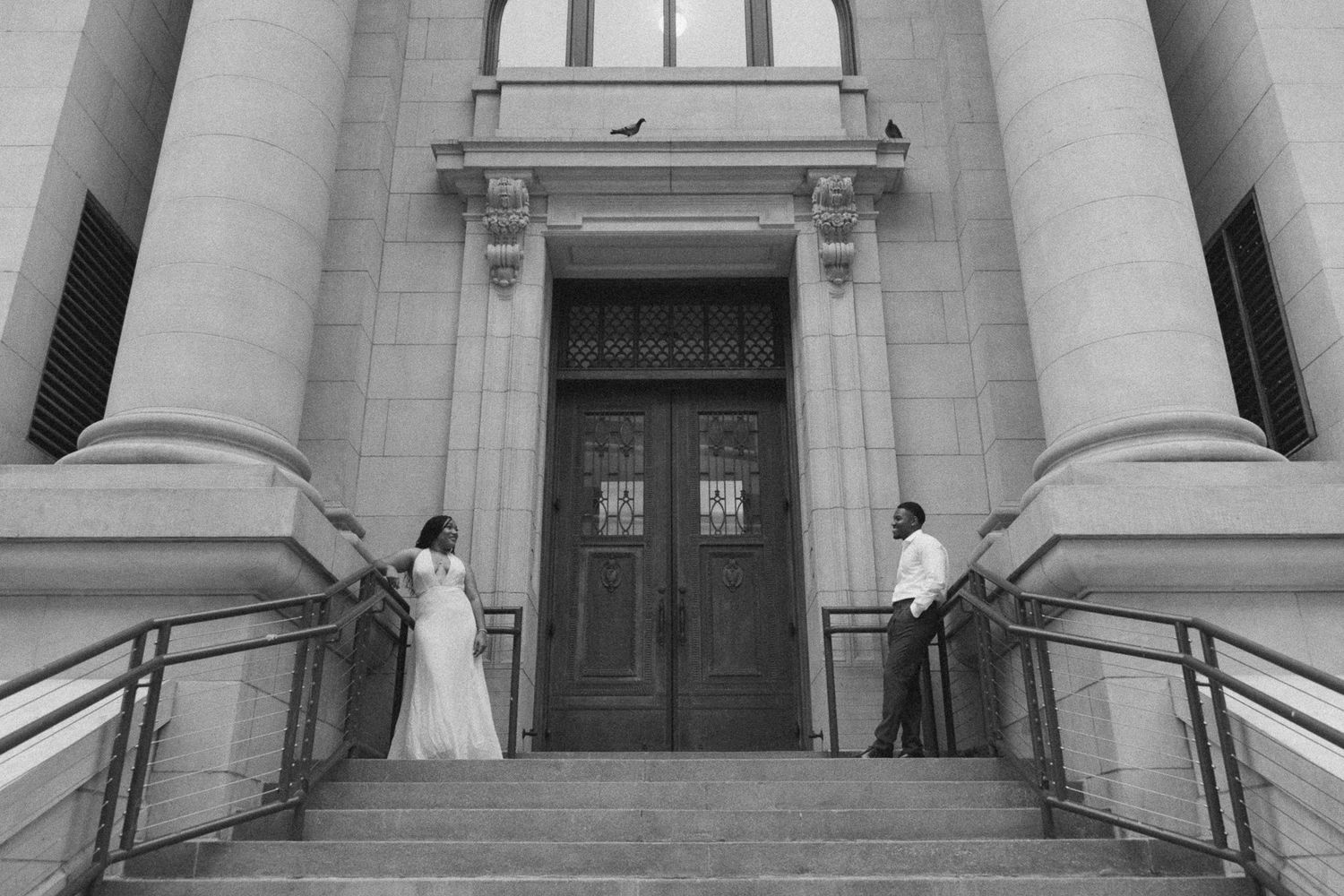 Architectural details of a courthouse entrance showing classical columns, stairs, and ornate doorways in black and white.