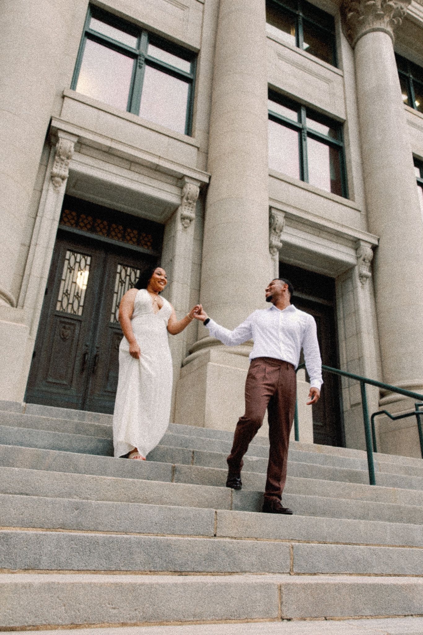 Two people in white and brown clothing interact on stone steps of a grand building with columns in a sequence of photos.