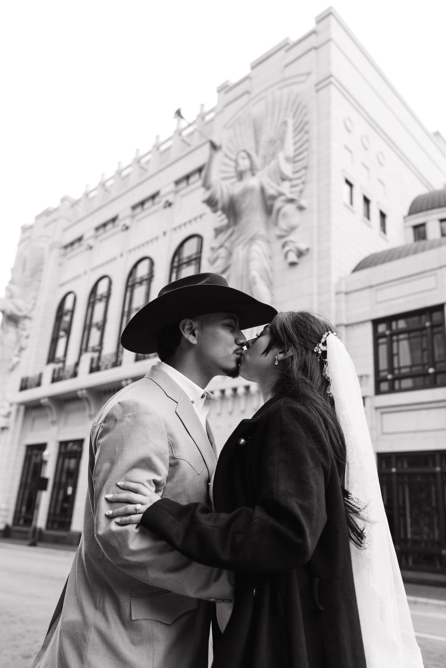 A romantic black and white photo sequence showing a couple kissing on a city street with historic buildings in the background.