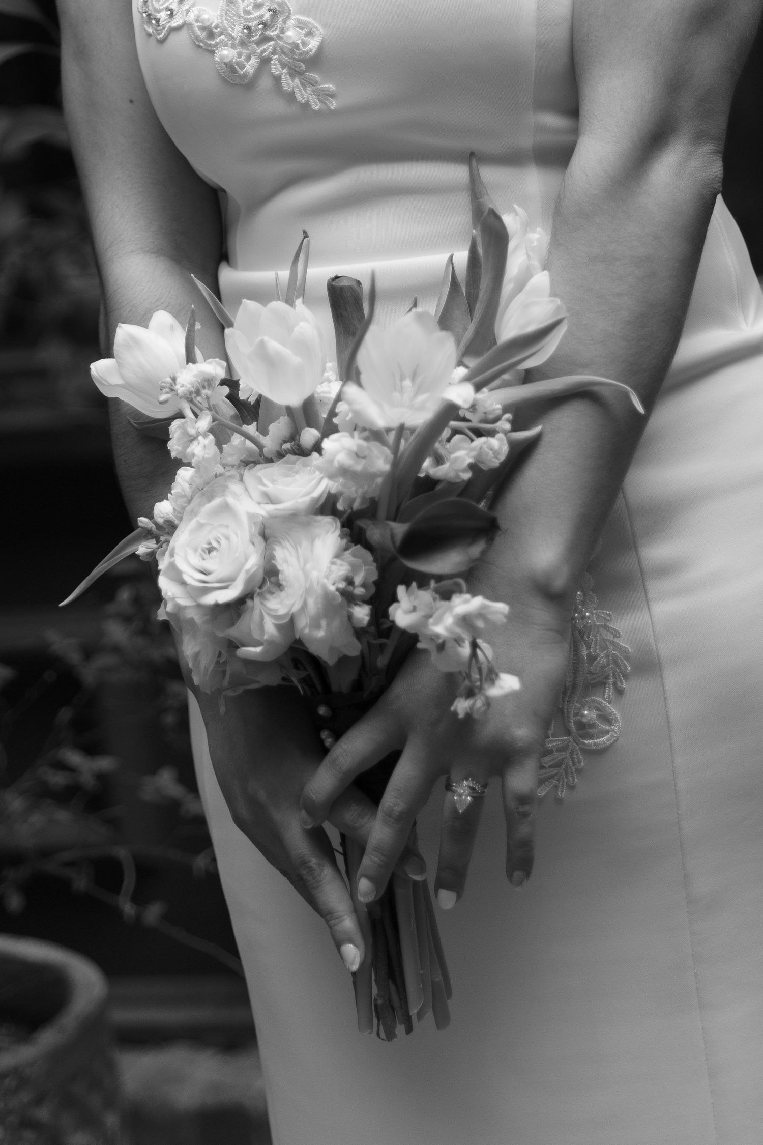 Black and white photo of a bride in a white gown holding a bouquet of roses and tulips at her wedding.