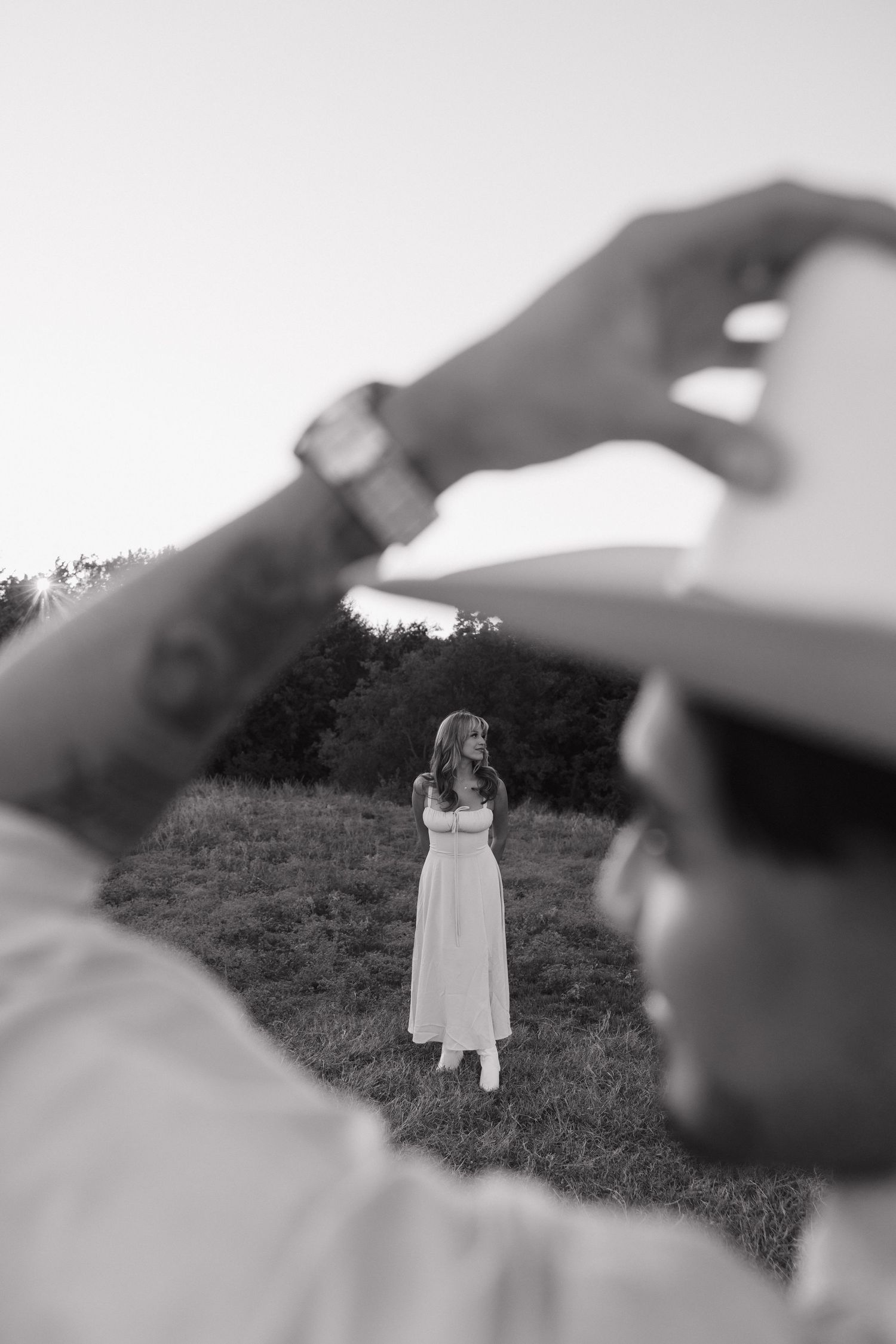 A dreamy black and white photo series shows a person in white standing on a grassy hillside in different perspectives.