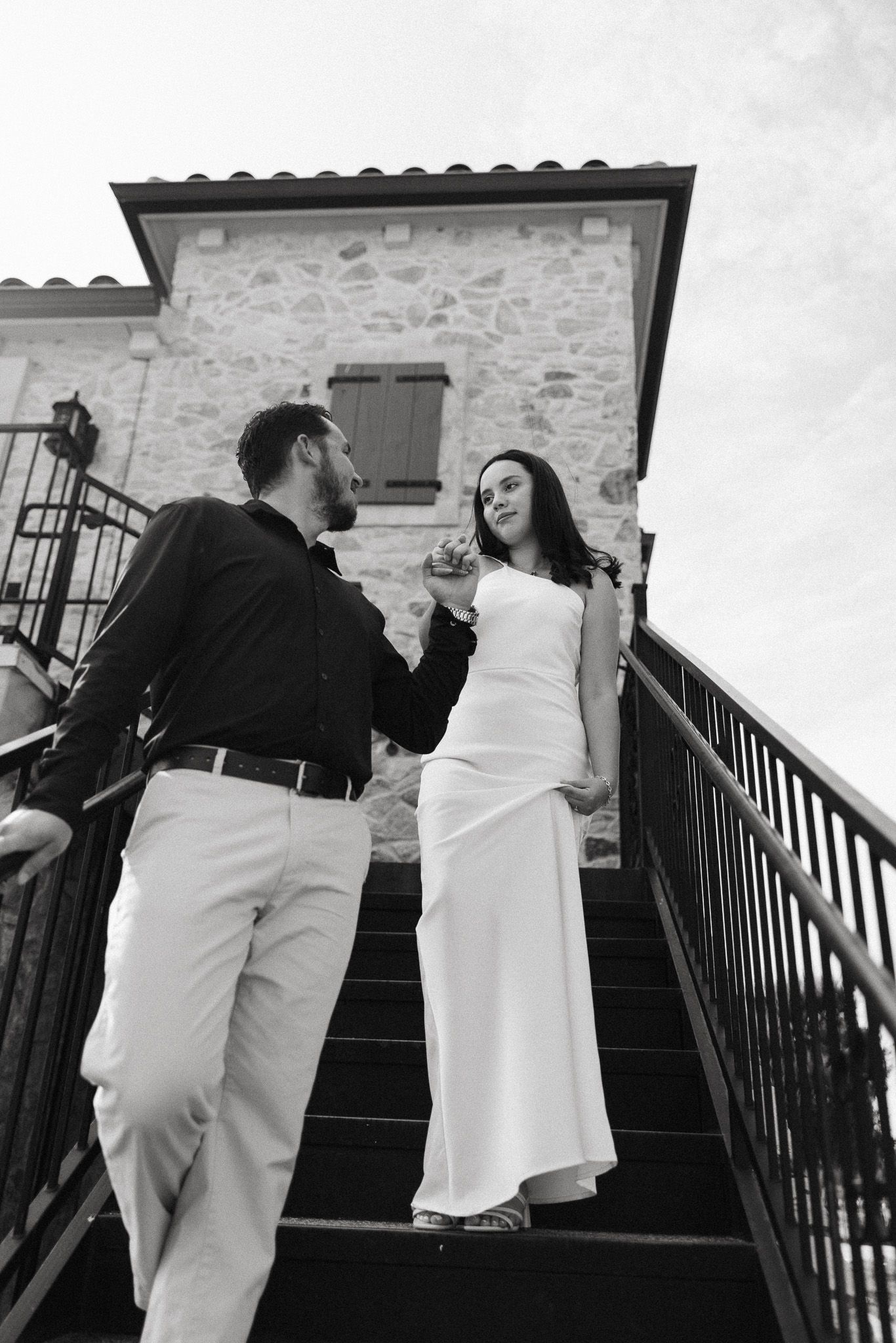 Black and white photos of a couple in formal wear on stone steps with iron railings.
