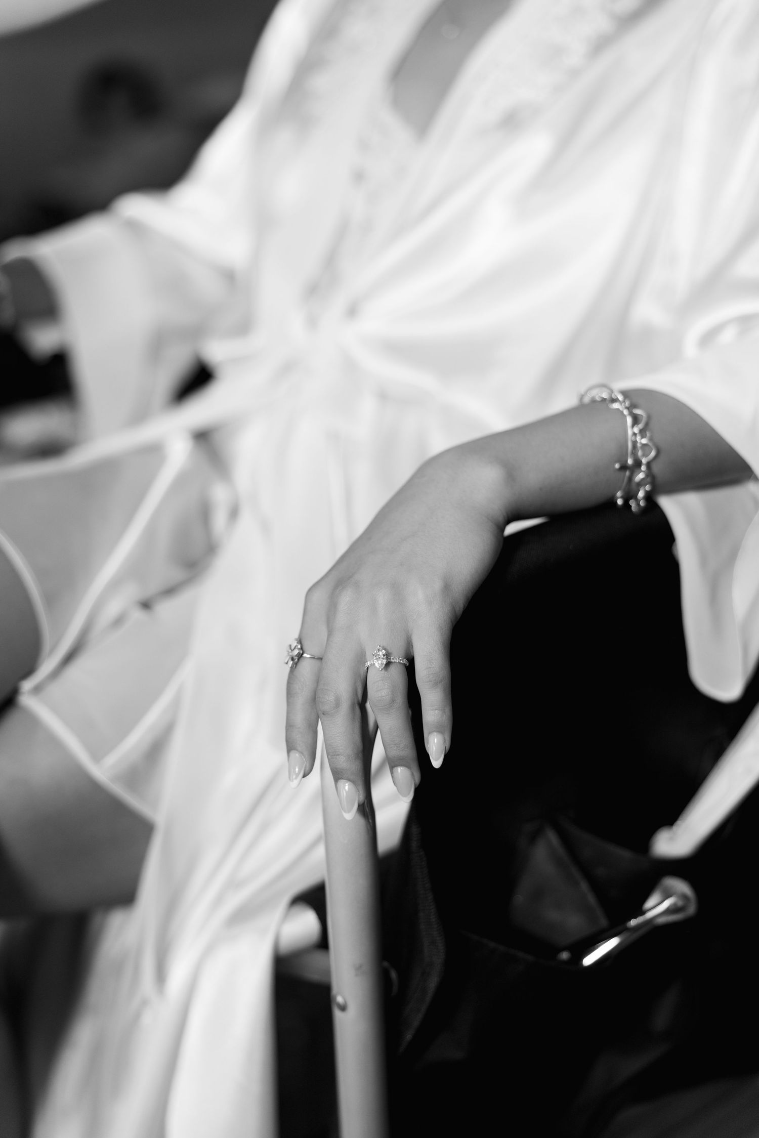 Bride in white robe showing elegant diamond ring and bracelet jewelry on her hand before wedding ceremony.