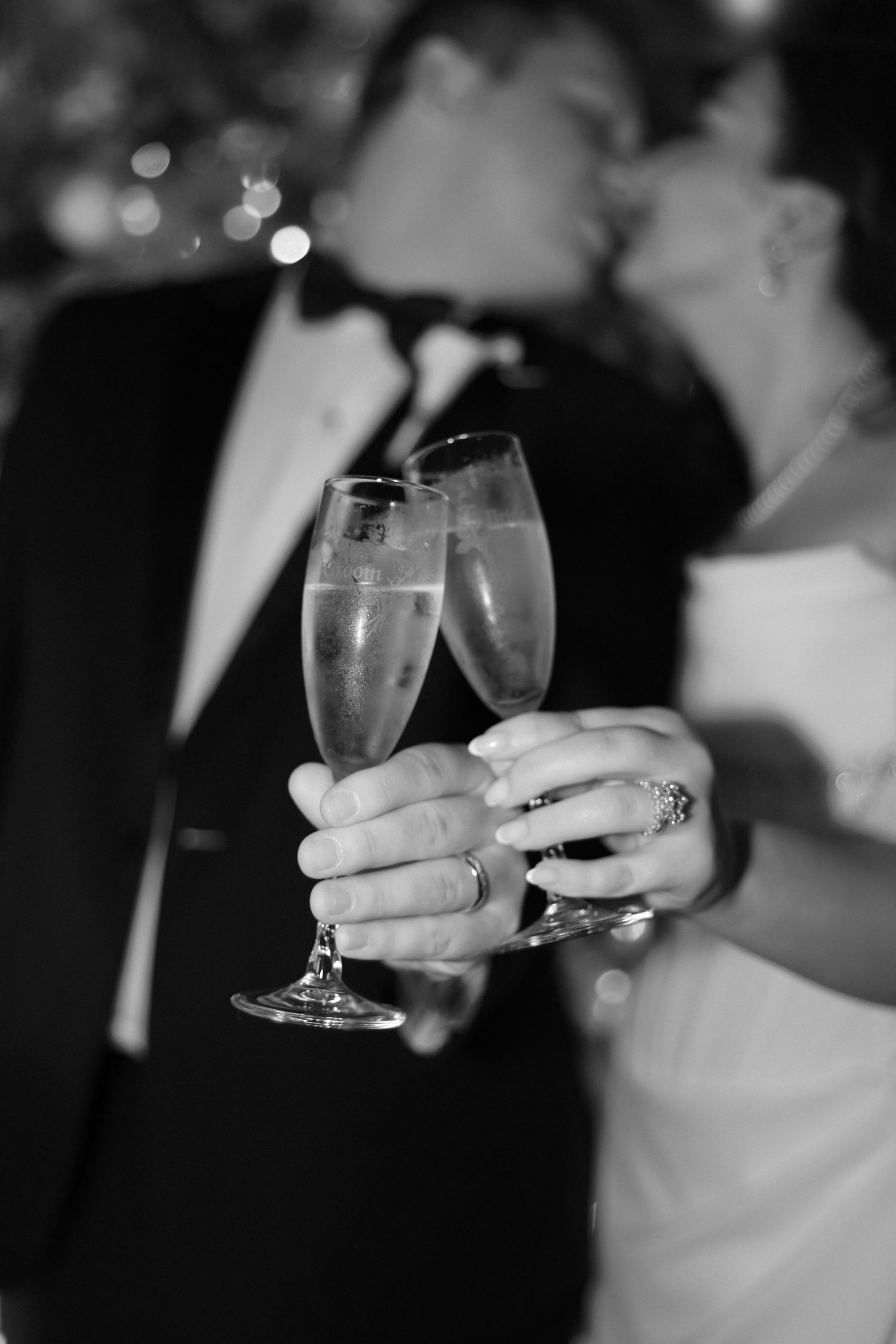 Black and white image showing hands holding champagne glasses during a celebratory toast at an event.