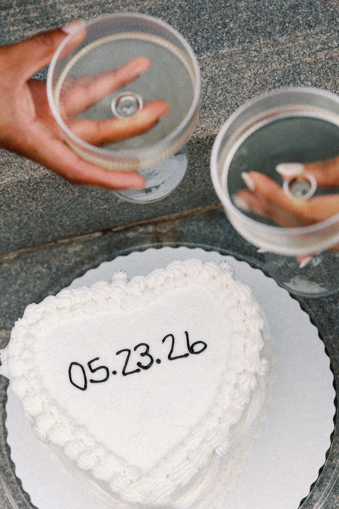 Two people toasting with Champagne over their engagment announcement cake.
