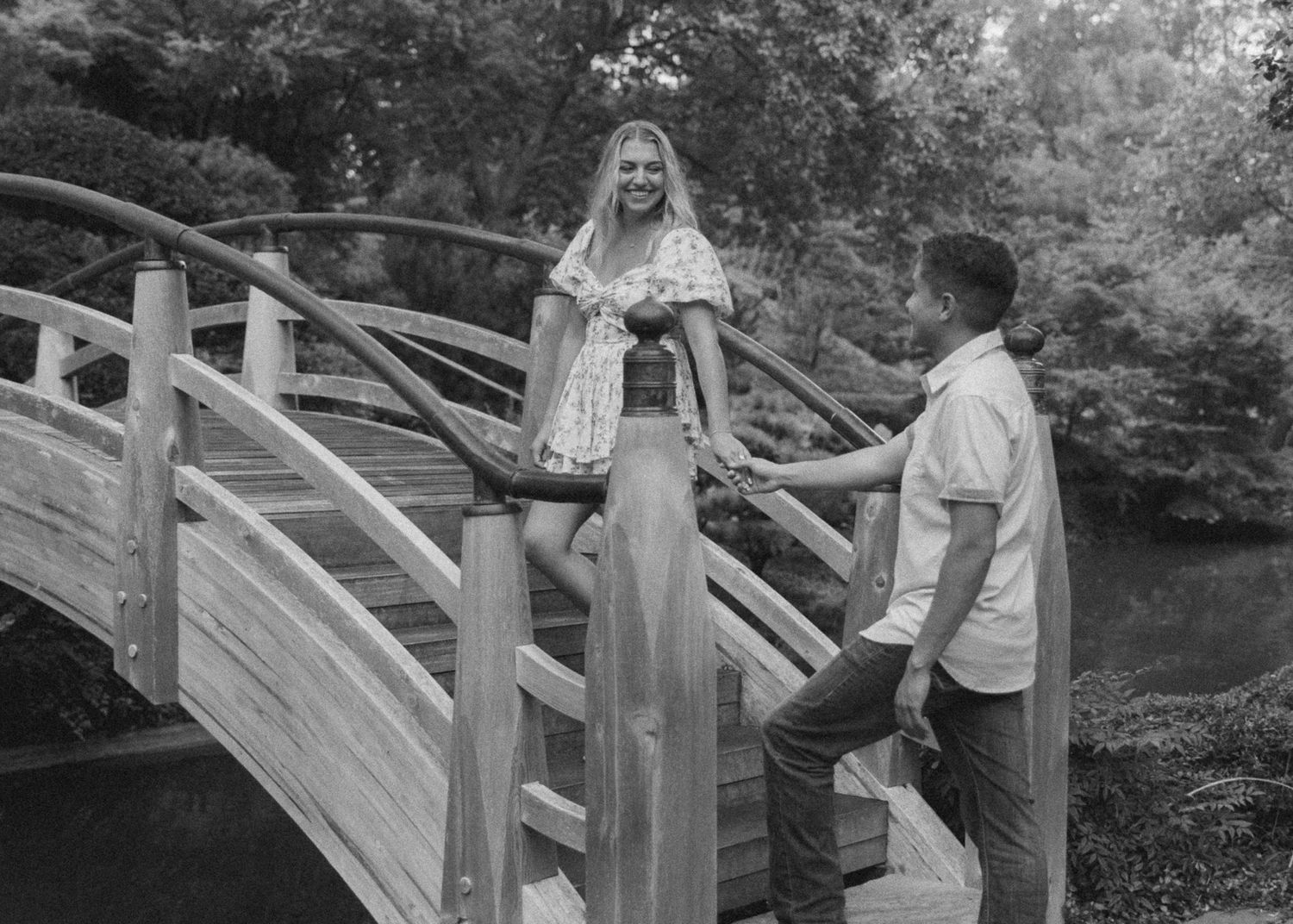 A couple walks up outdoor wooden steps in a garden setting during a photo session.