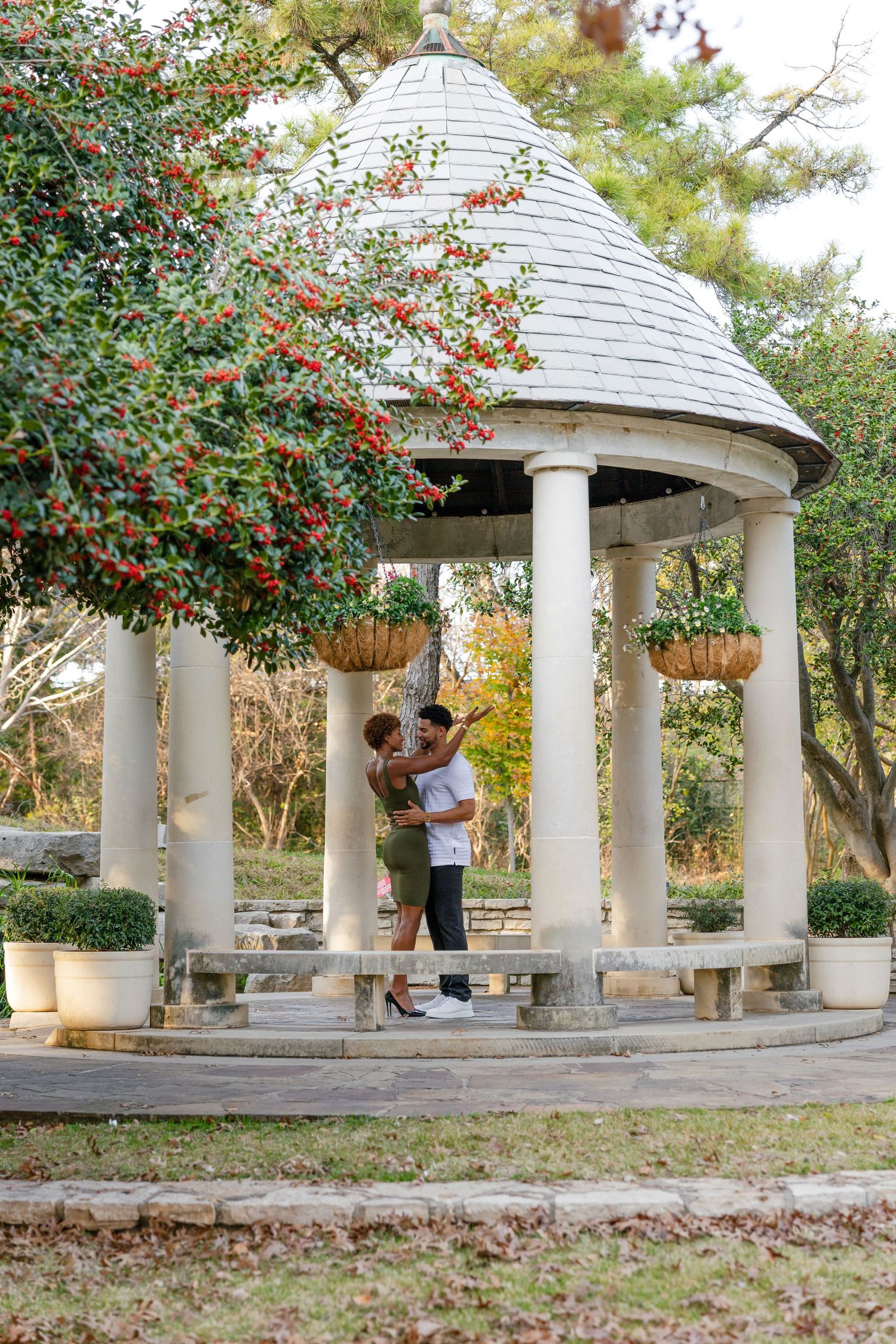 A romantic gazebo surrounded by autumn trees and red berries creates an intimate outdoor setting for a couple.